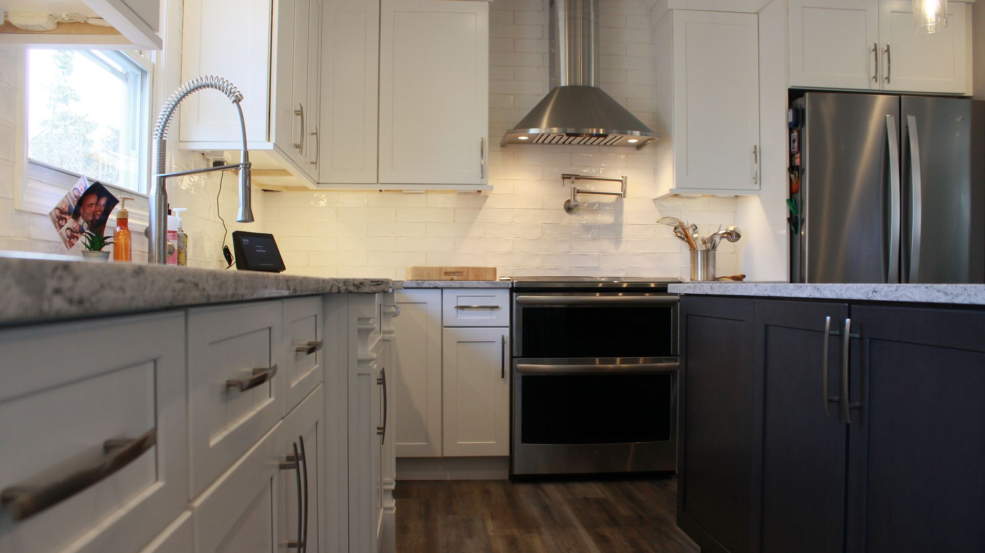 A modern kitchen with white and dark gray cabinets, stainless steel appliances, and a light-colored countertop.