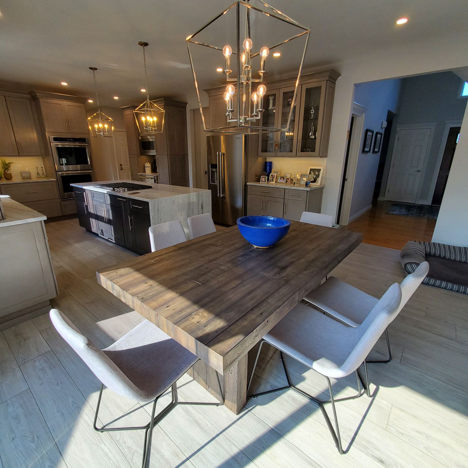 A modern kitchen and dining area with a wooden table, chairs, and a chandelier.