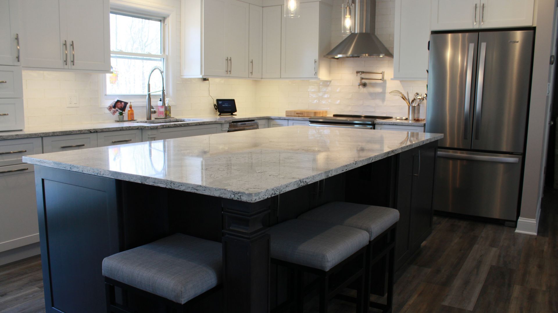 Modern kitchen with white and gray cabinets, granite countertop island, and stainless steel appliances.