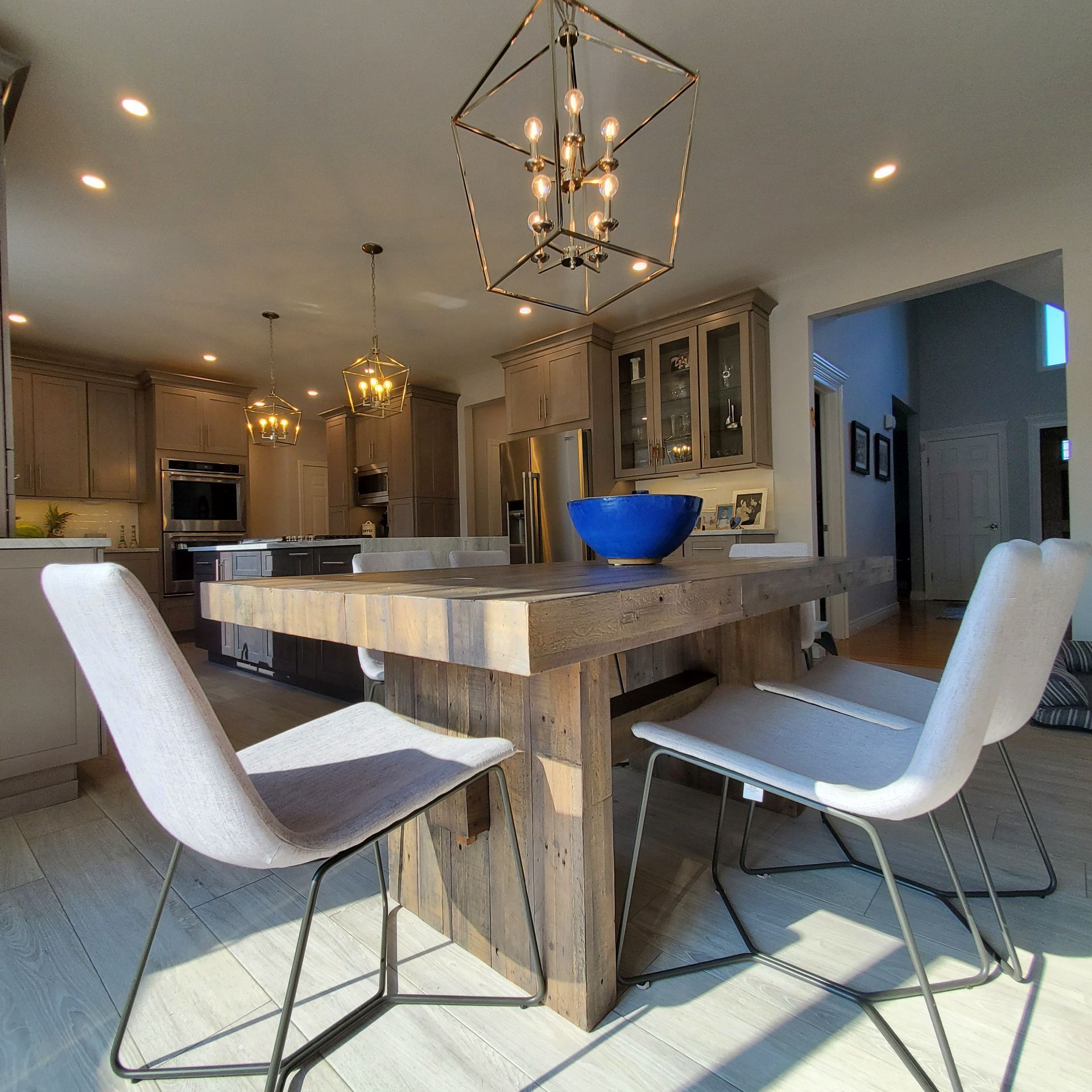 Kitchen with wood island, pendant lights, light grey cabinets, two chairs, and a blue bowl.