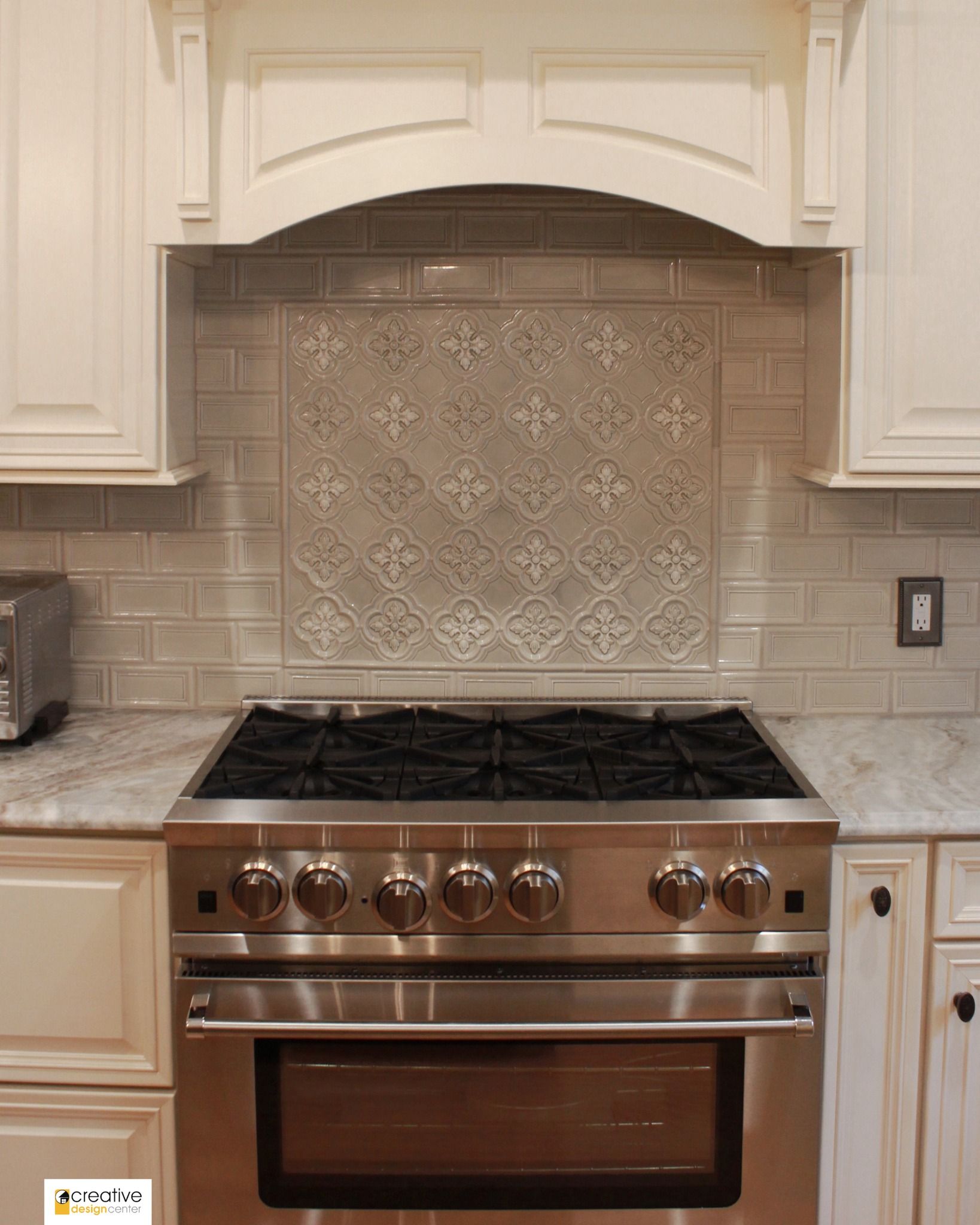A stainless steel stove top oven in a kitchen with white cabinets.