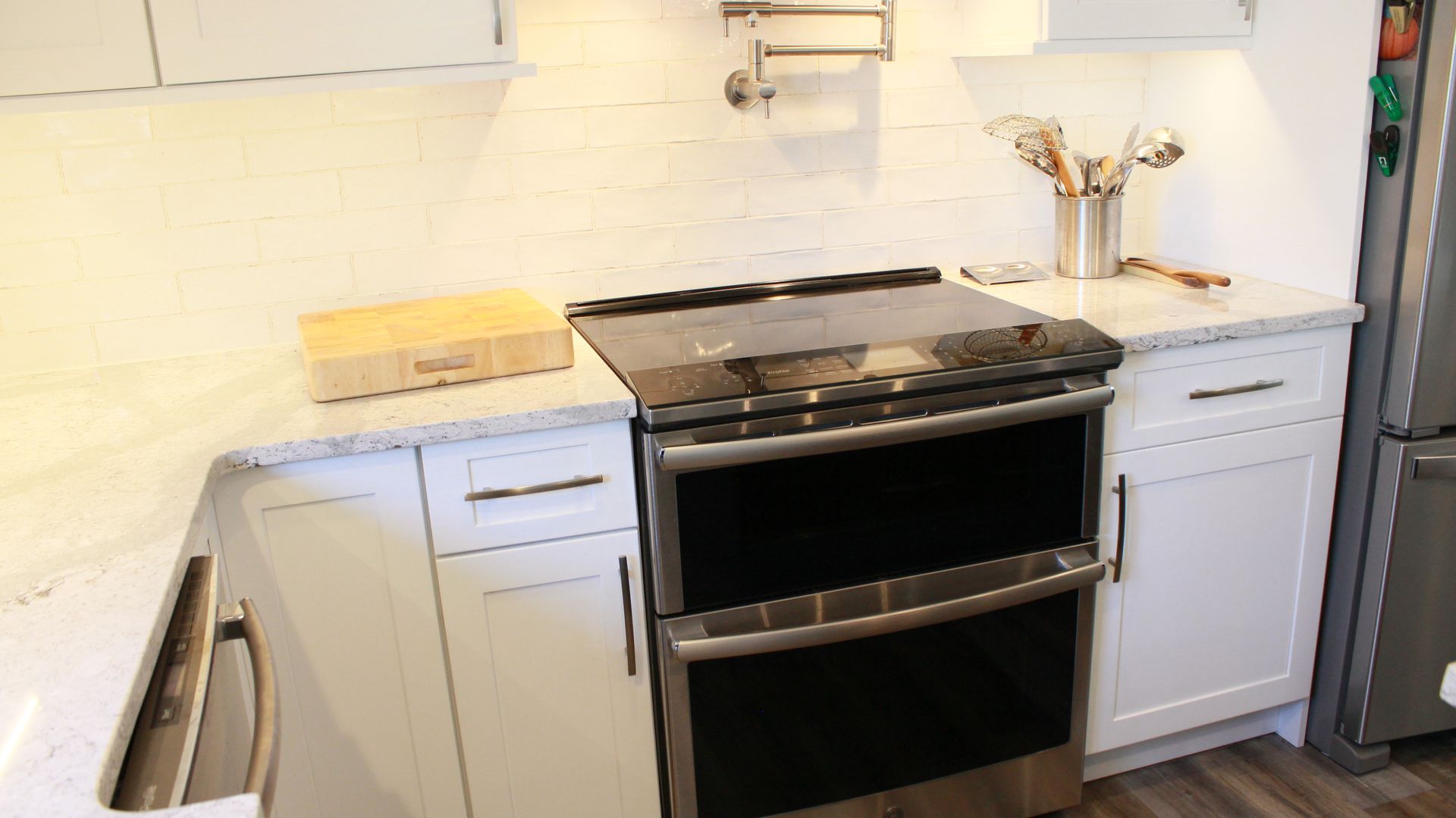 Kitchen with a stove, white cabinets, and a cutting board on the counter.