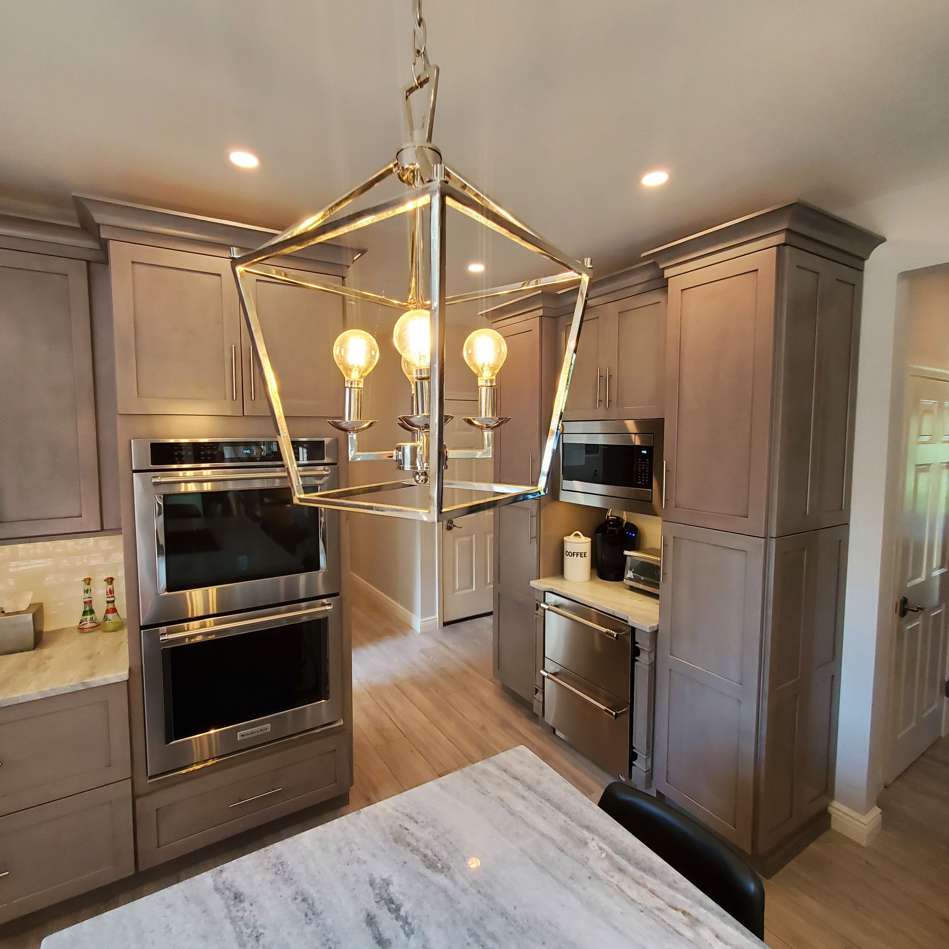 Kitchen with gray cabinets, stainless steel appliances, and a geometric light fixture.