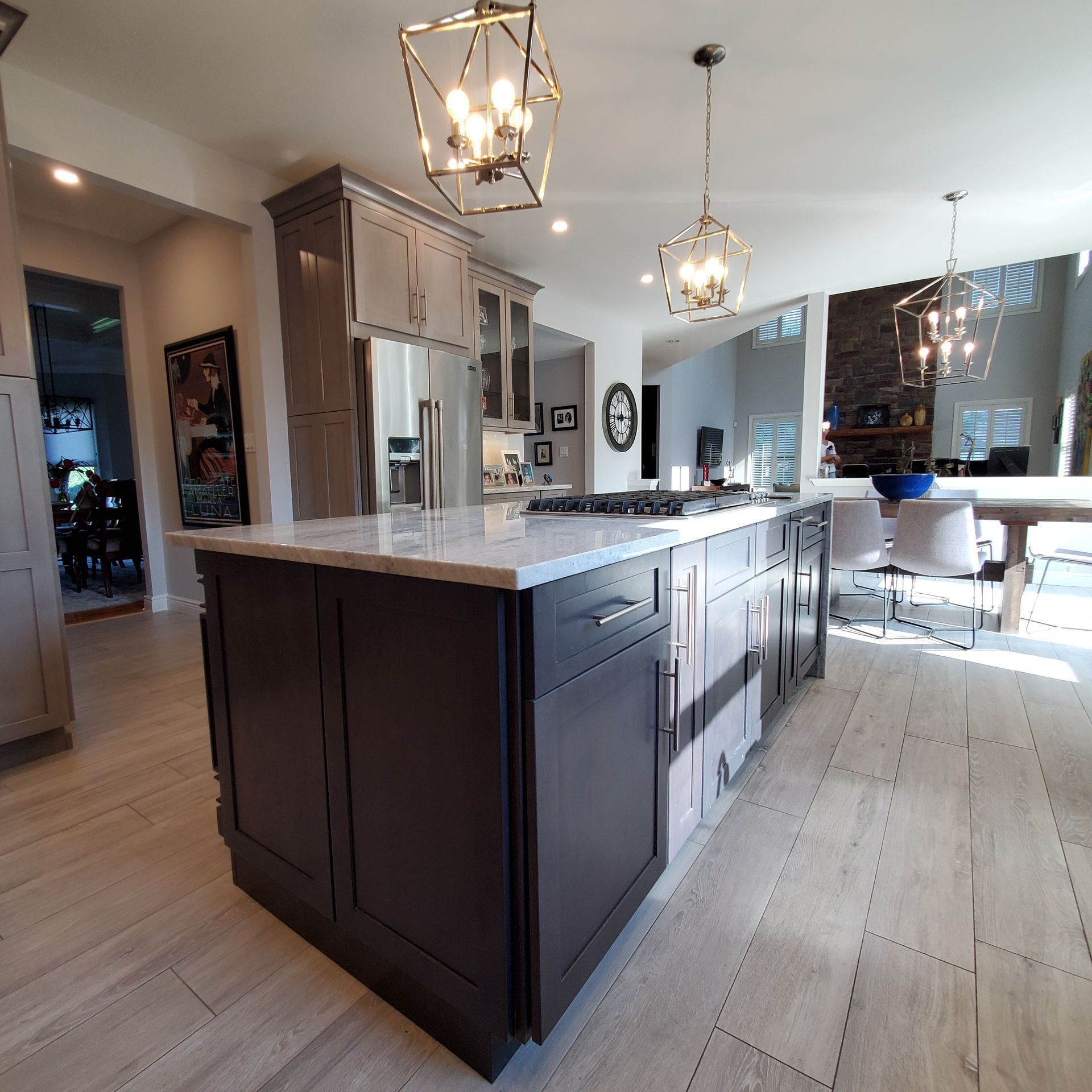 Modern kitchen with a dark island, light countertops, and gold pendant lights.
