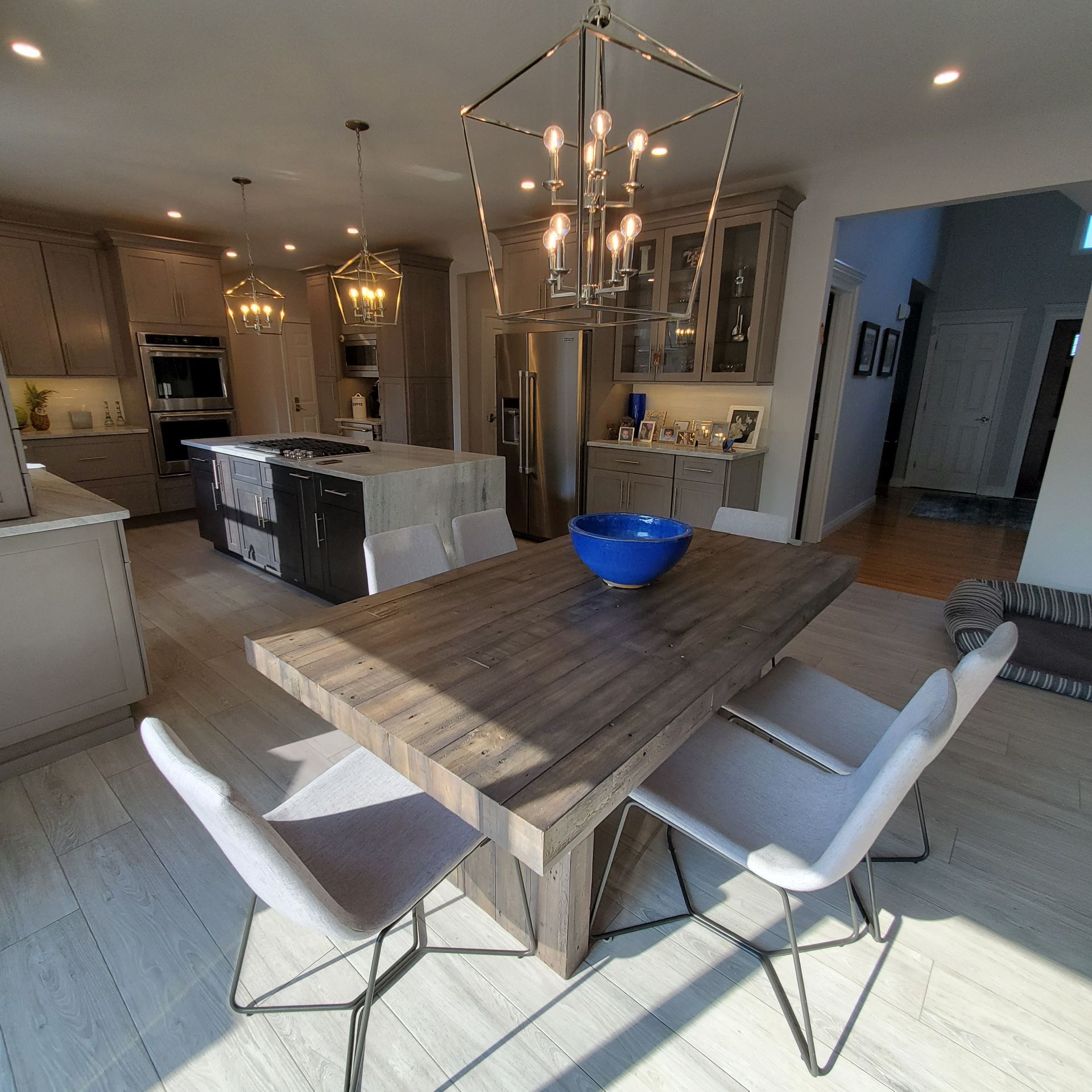 Kitchen with a wooden table, blue bowl, chairs, and overhead lights.