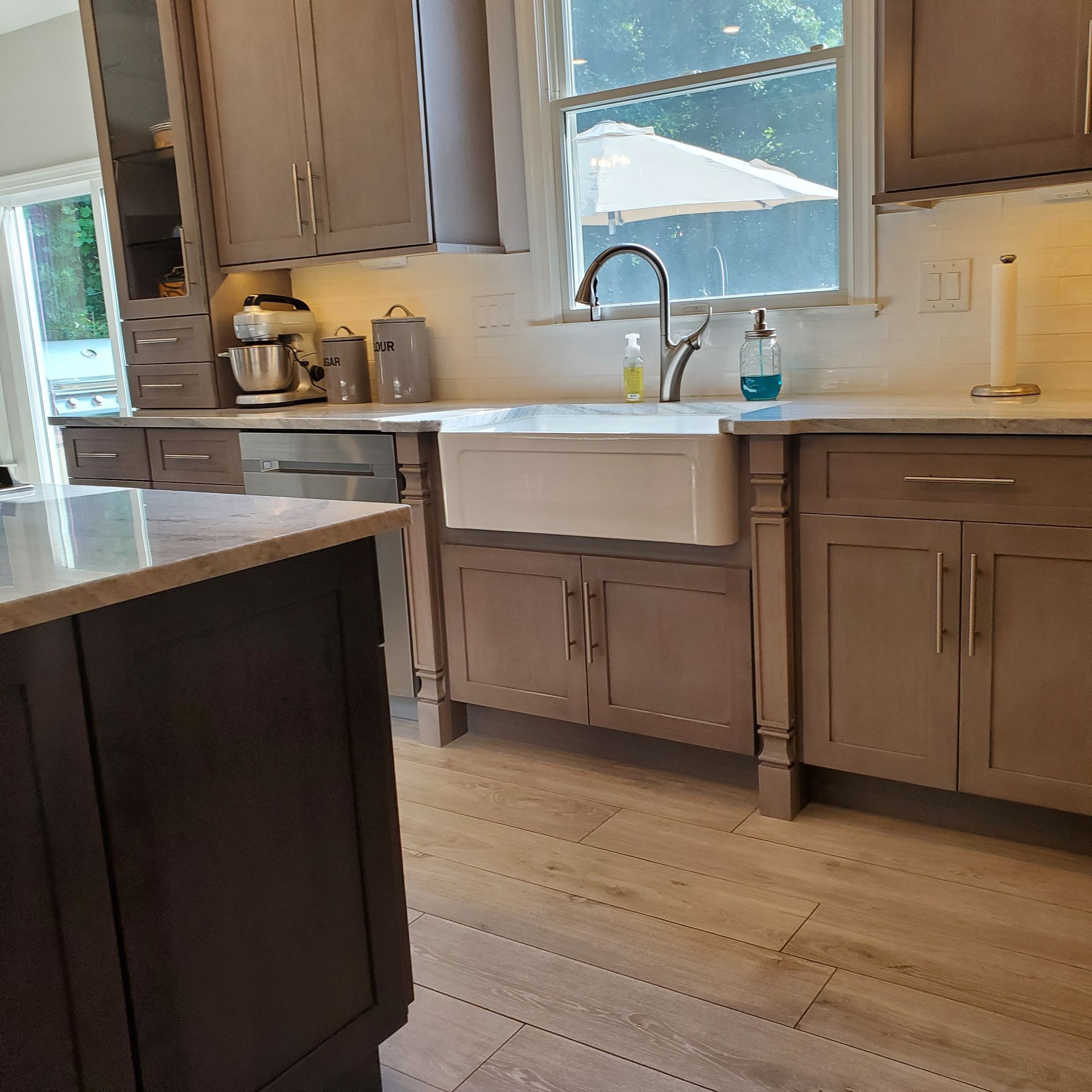 Kitchen with gray cabinetry, white farmhouse sink, and a window with natural light.