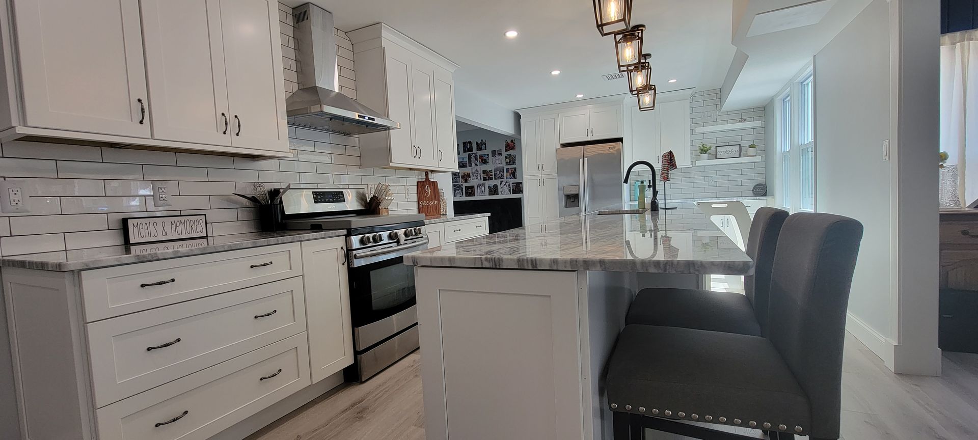 Bright white kitchen with stainless steel appliances, island with seating, light gray floors.
