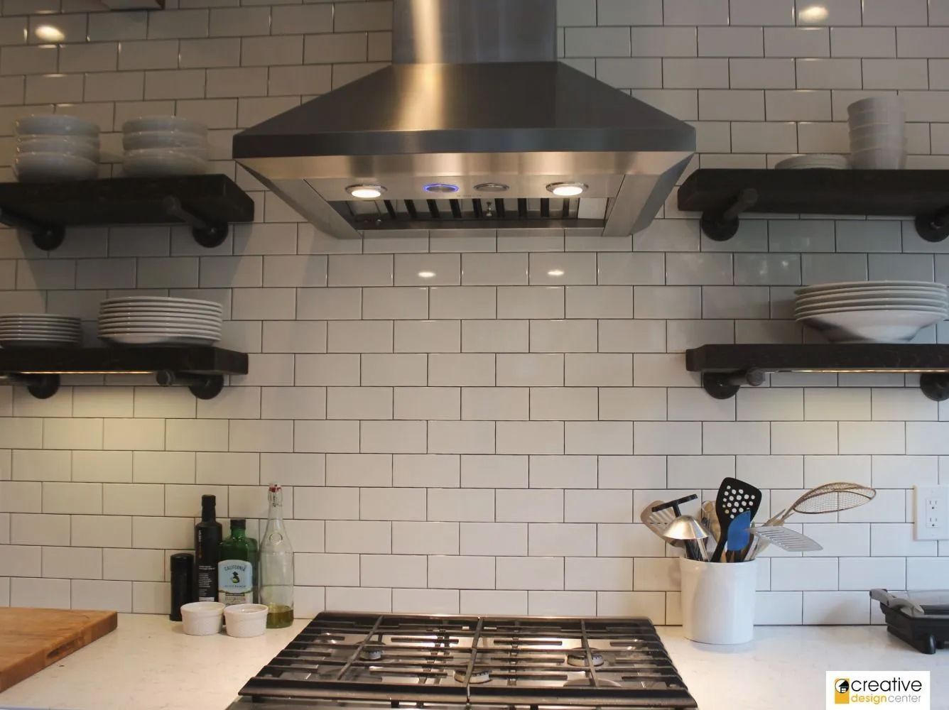 A kitchen with a stove top oven and a hood above it