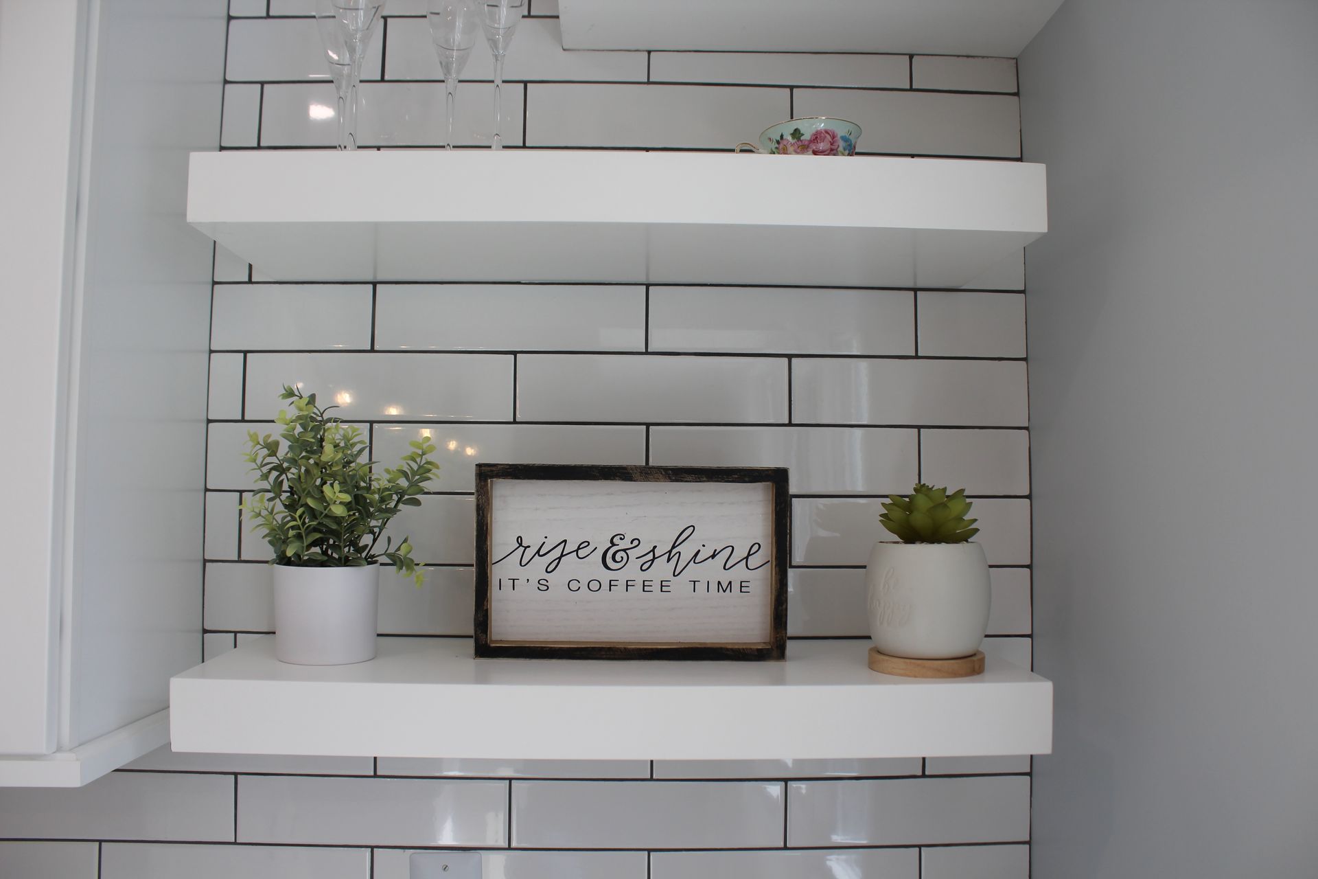 Two kitchen sections: stainless steel refrigerator with white cabinets above, and white cabinets, countertops, and shelves.