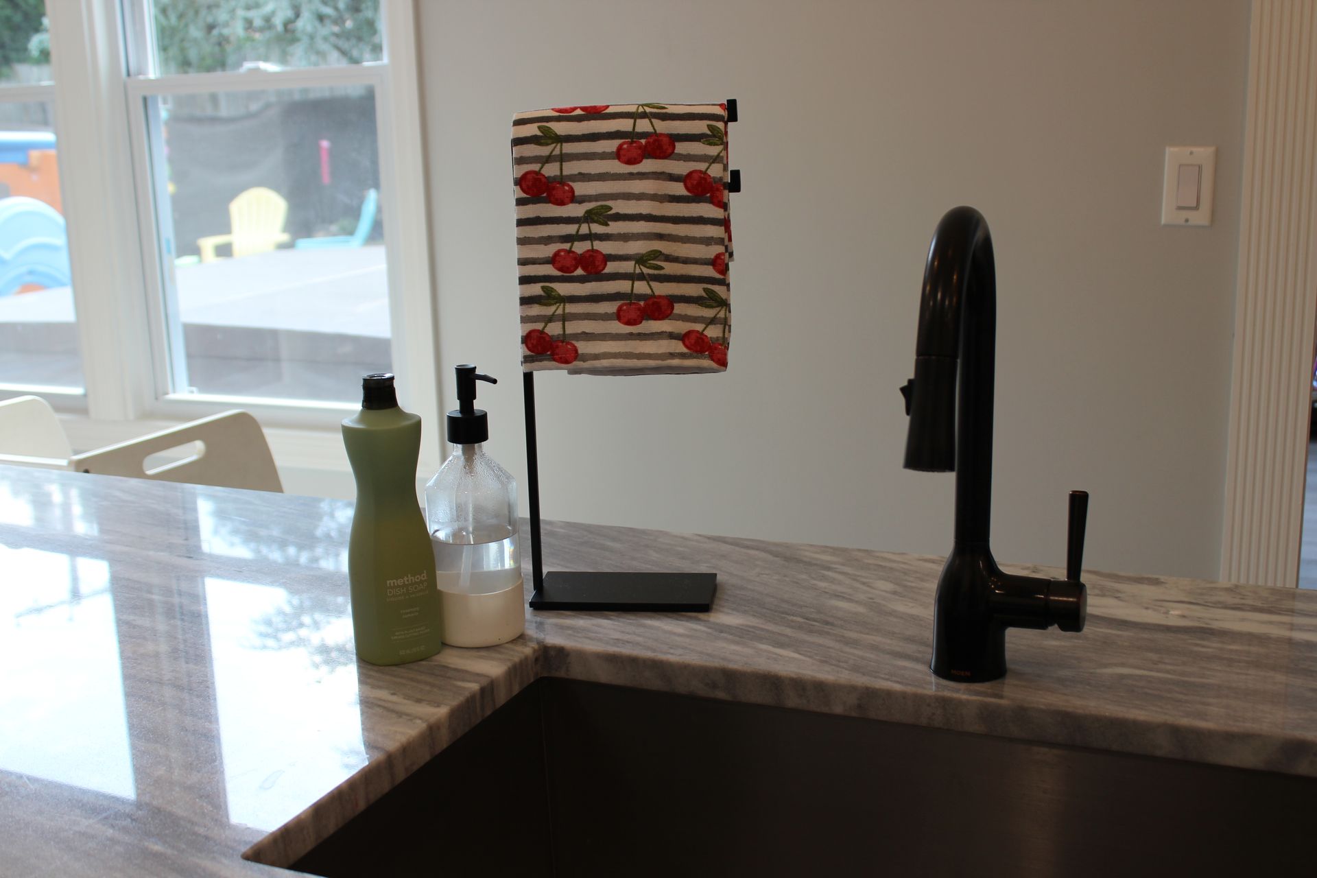 Kitchen counter with gray and white marble pattern, white cabinets, and subway tile backsplash.