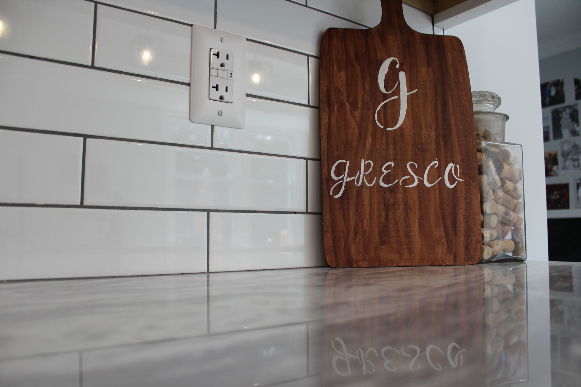 Modern white kitchen with island, pendant lights, and wood-look flooring. Stainless steel appliances.