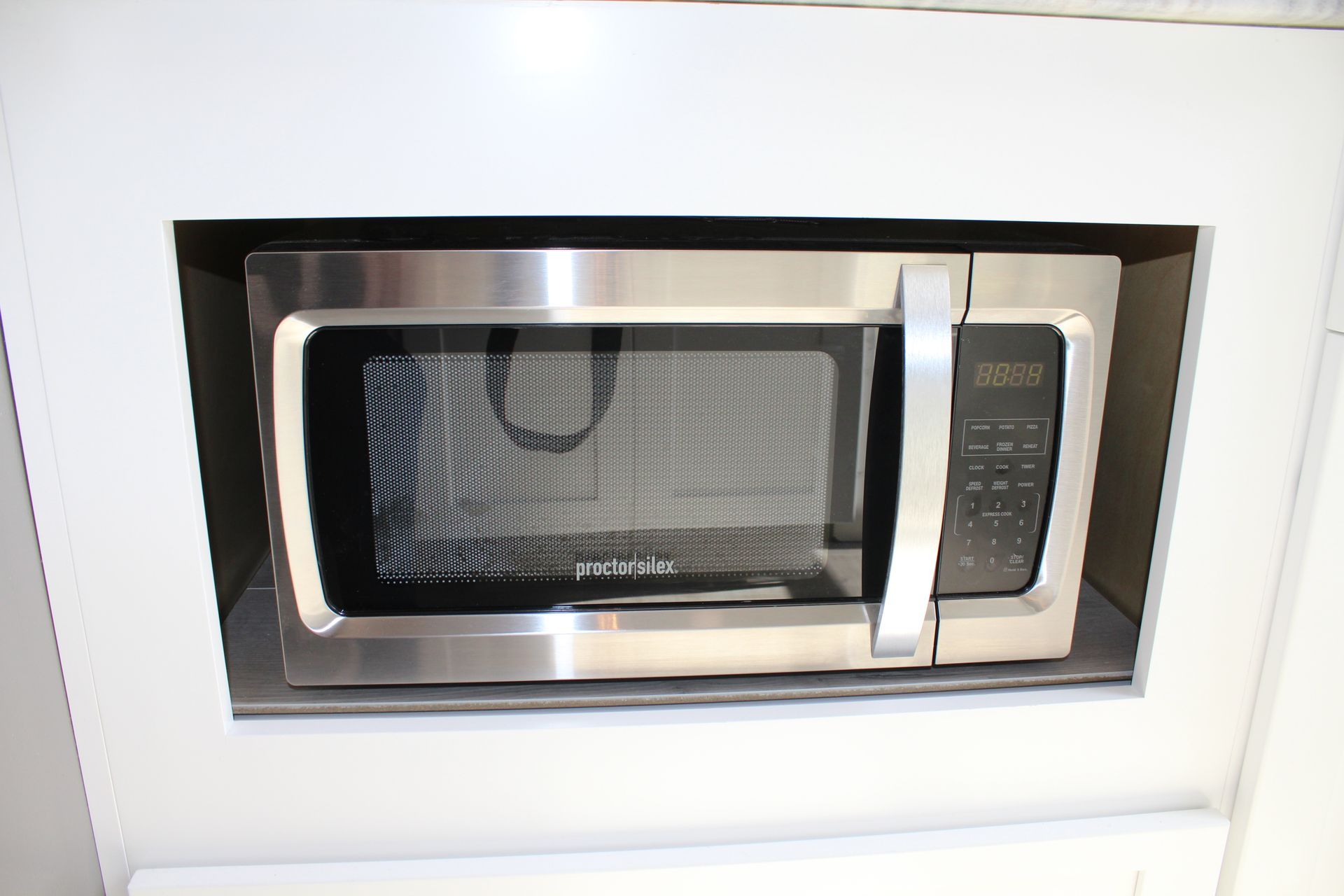 White kitchen with light wood floors, stainless steel appliances, and a large island.