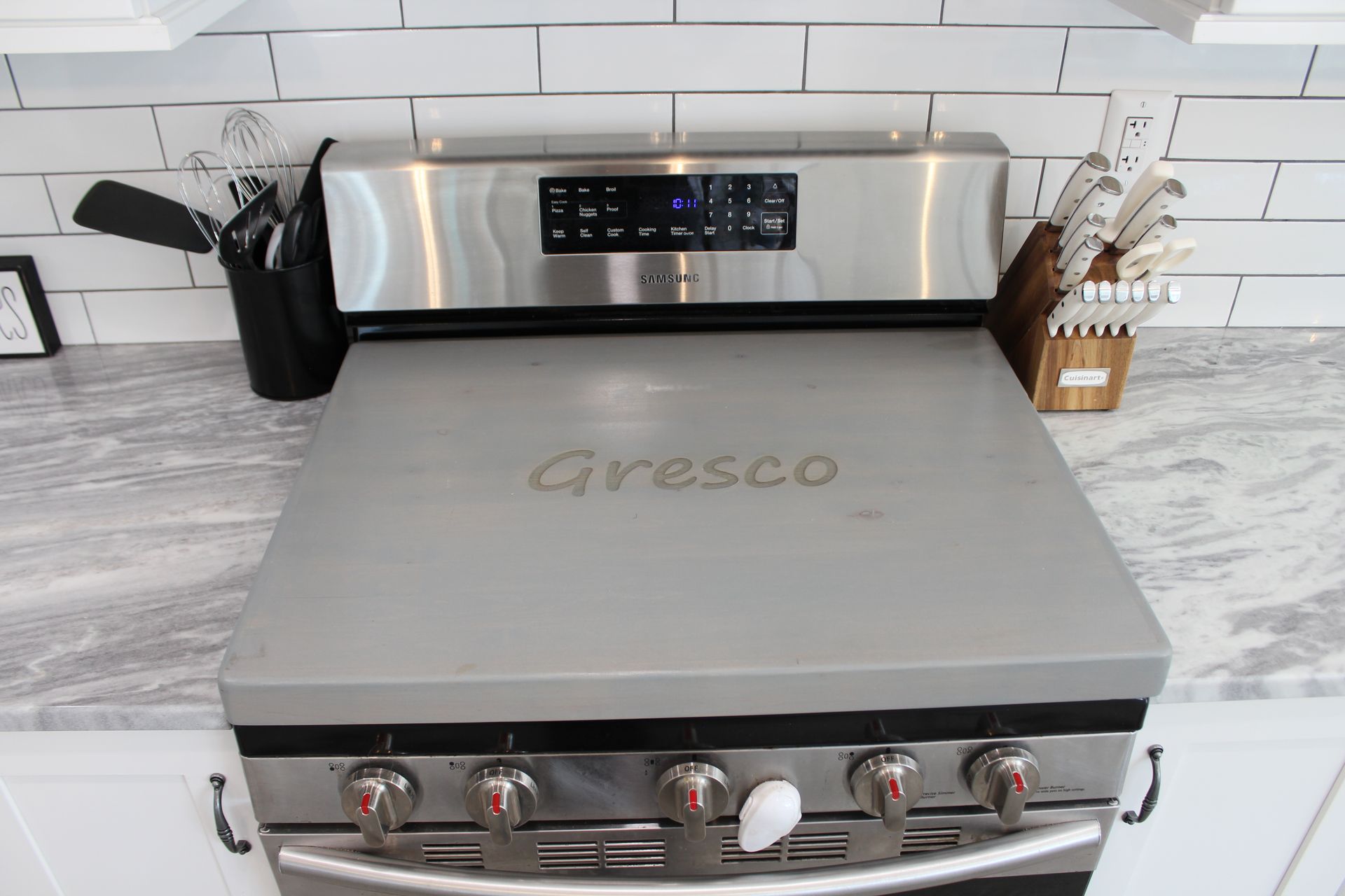 Modern white kitchen with stainless steel appliances, large island, and pendant lights.