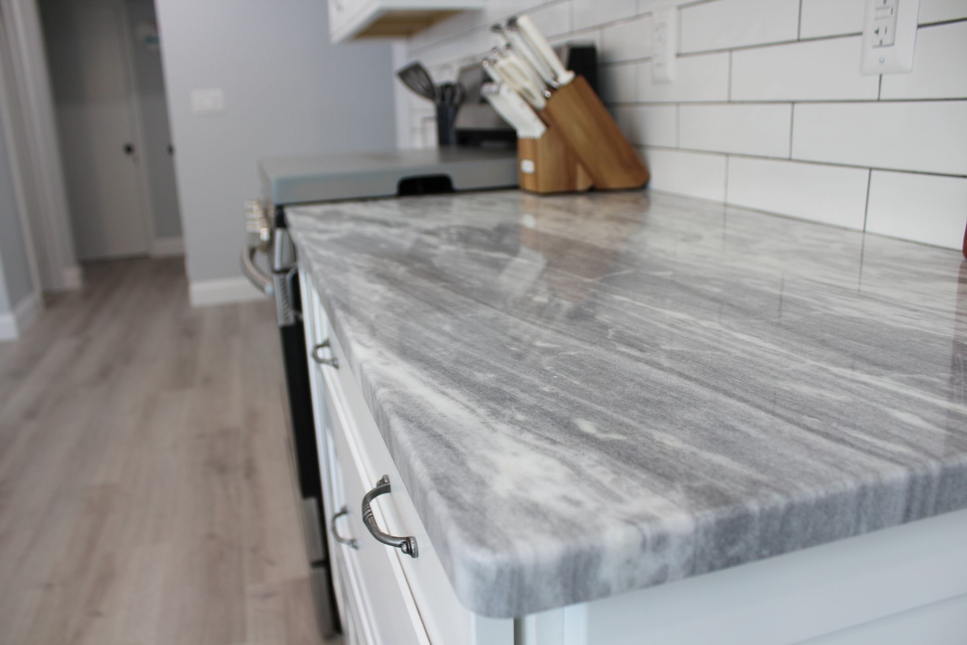 Kitchen sink with faucet, cherry-printed towel, soap and dish soap, and window in the background.