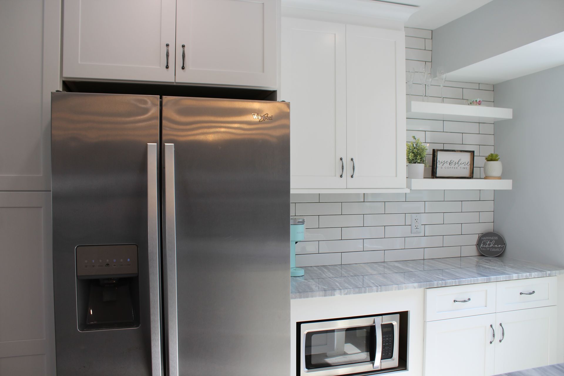 White shelves with plants and a sign against a tiled wall.