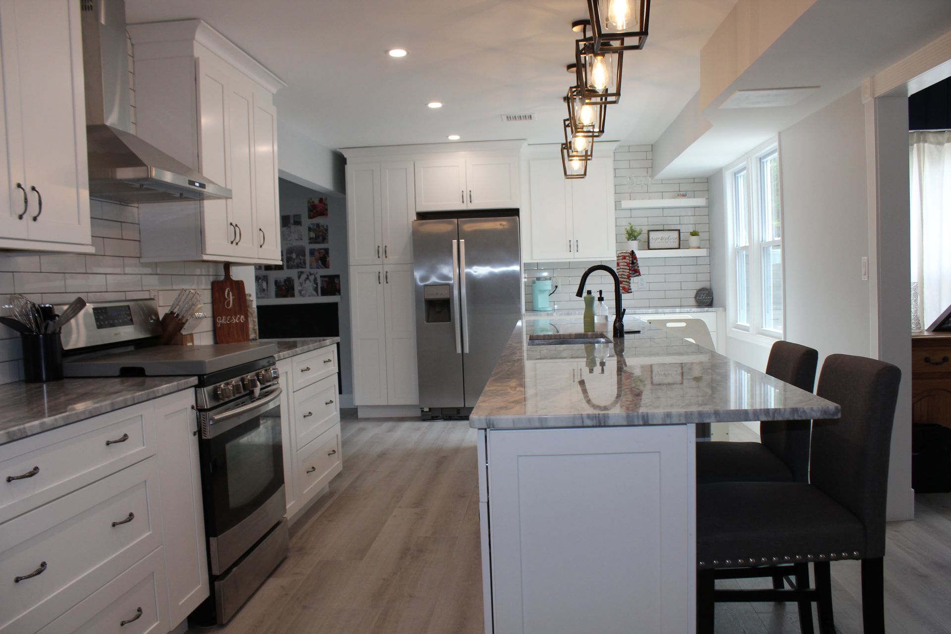 Modern kitchen with white cabinets, stainless steel appliances, and a granite countertop island.