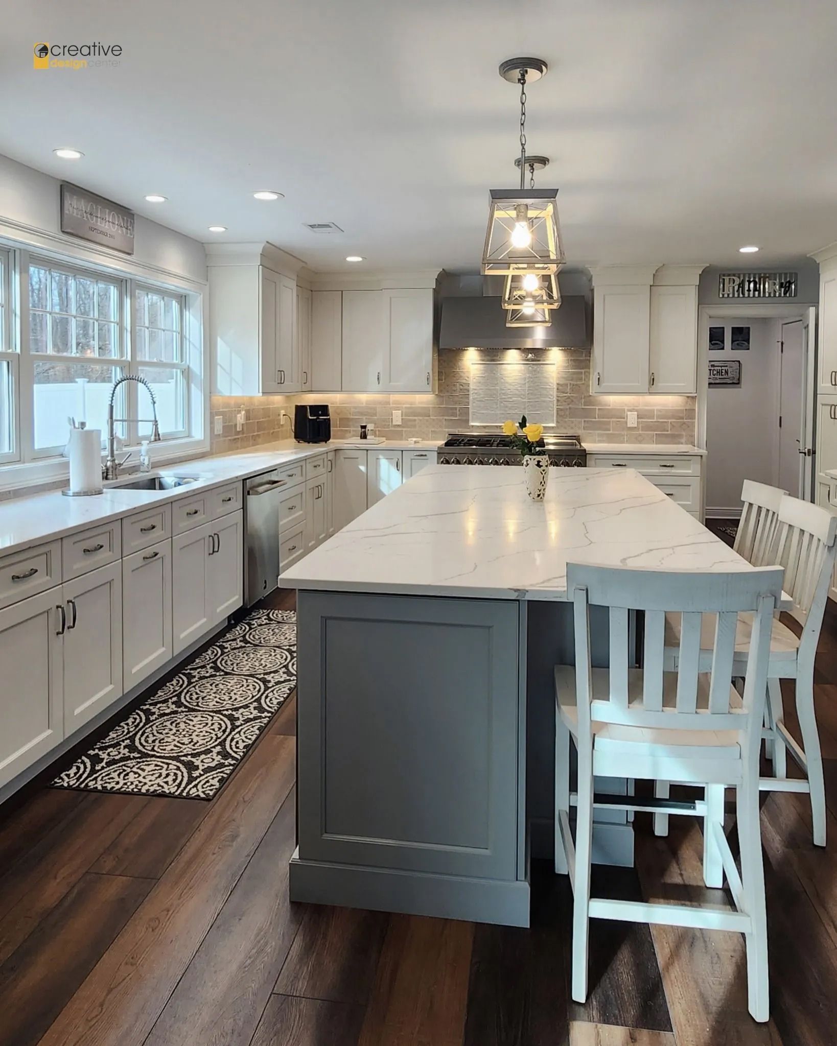 A kitchen with white cabinets and a large island in the middle.