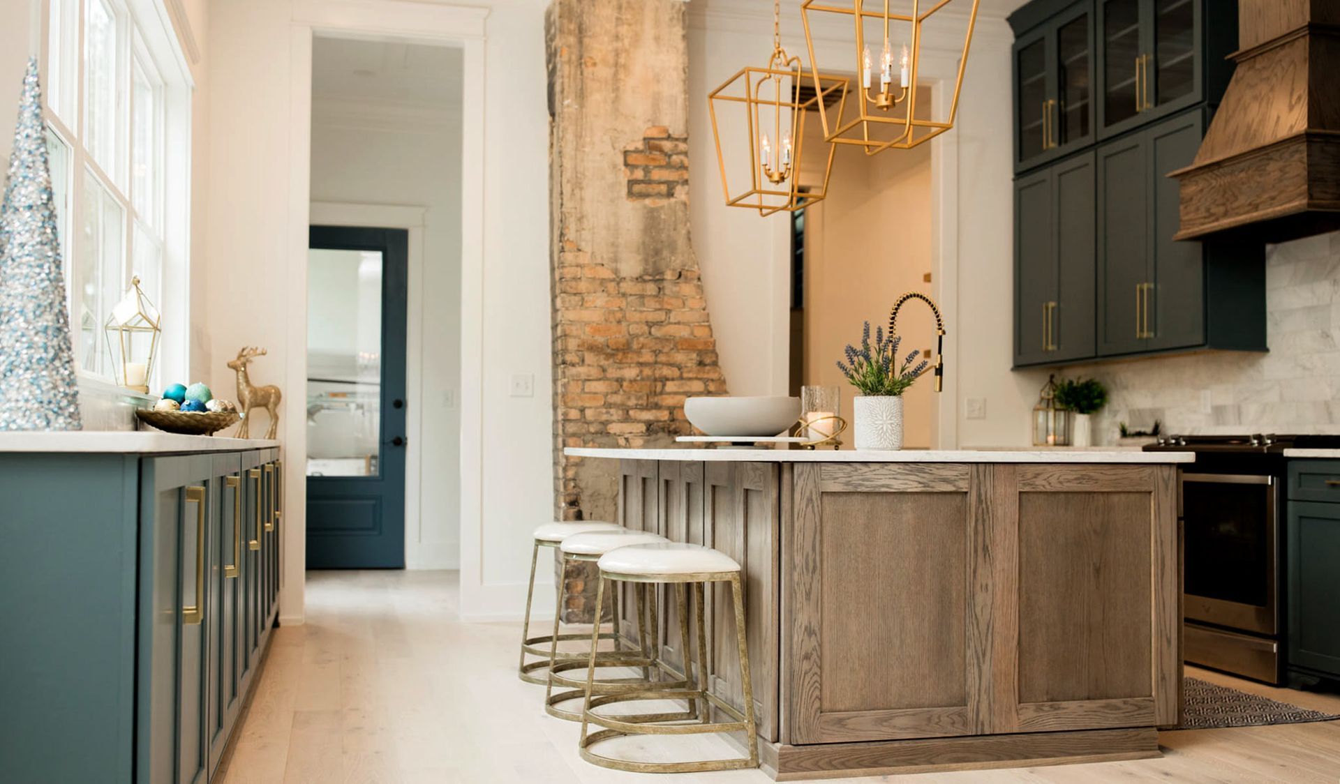 Kitchen with blue cabinets, wood island, exposed brick, and gold accents.