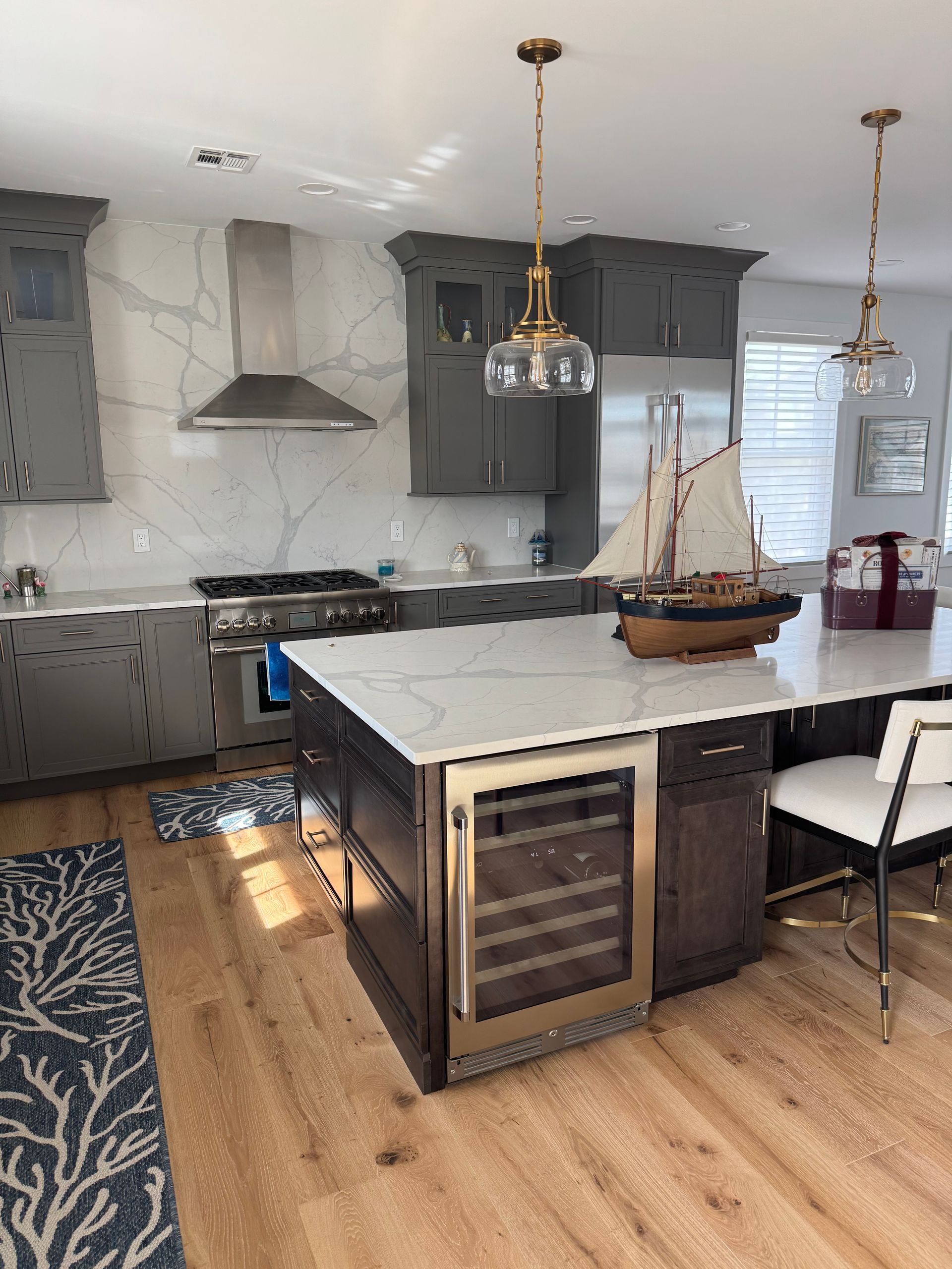 Modern kitchen with marble island, gray cabinets, wood floors, and hanging pendant lights