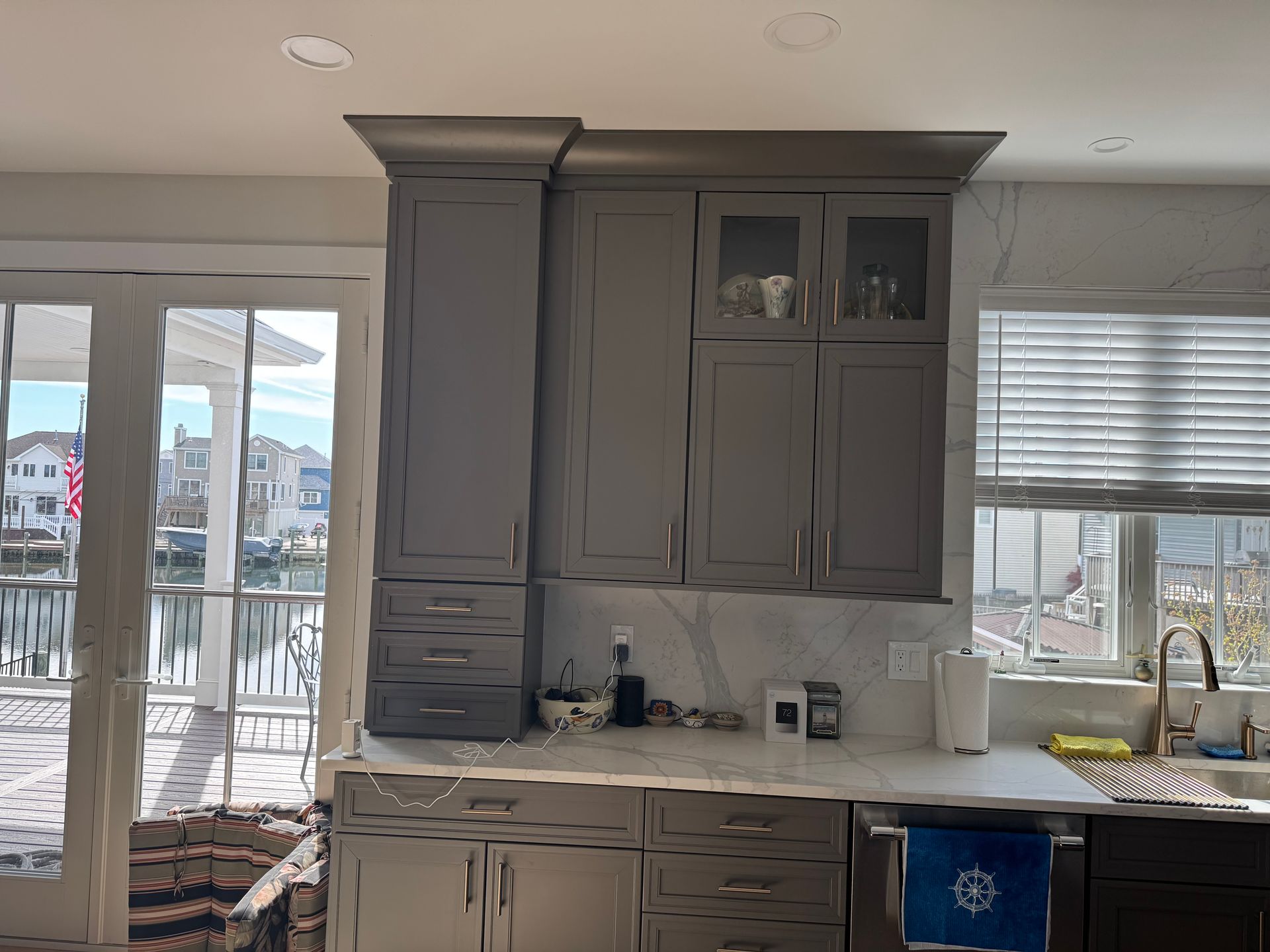 Kitchen with gray cabinets, white countertops, and large windows overlooking a waterfront view.