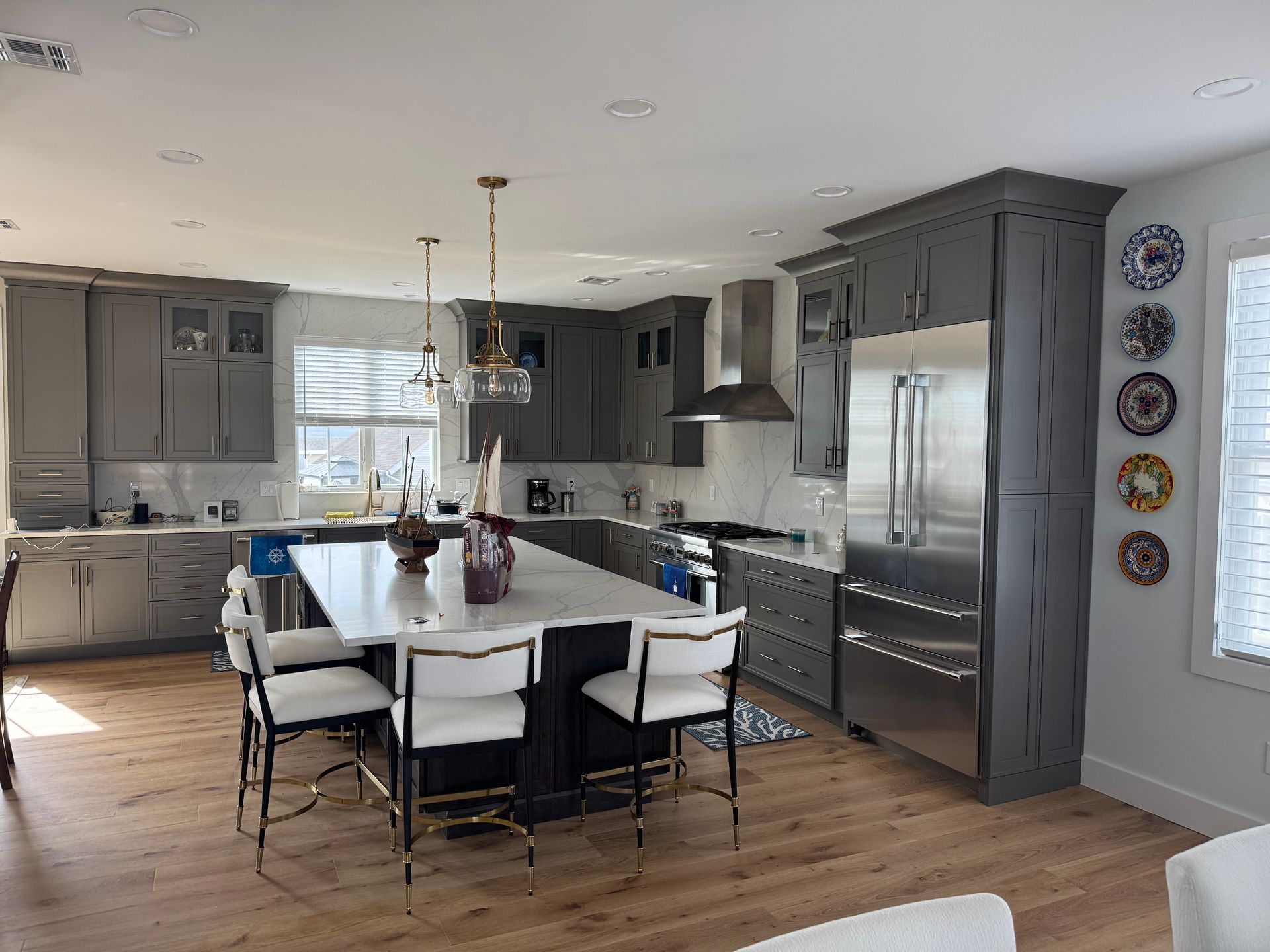 Modern kitchen with gray cabinets, white island, stainless appliances, and colorful plates on the wall
