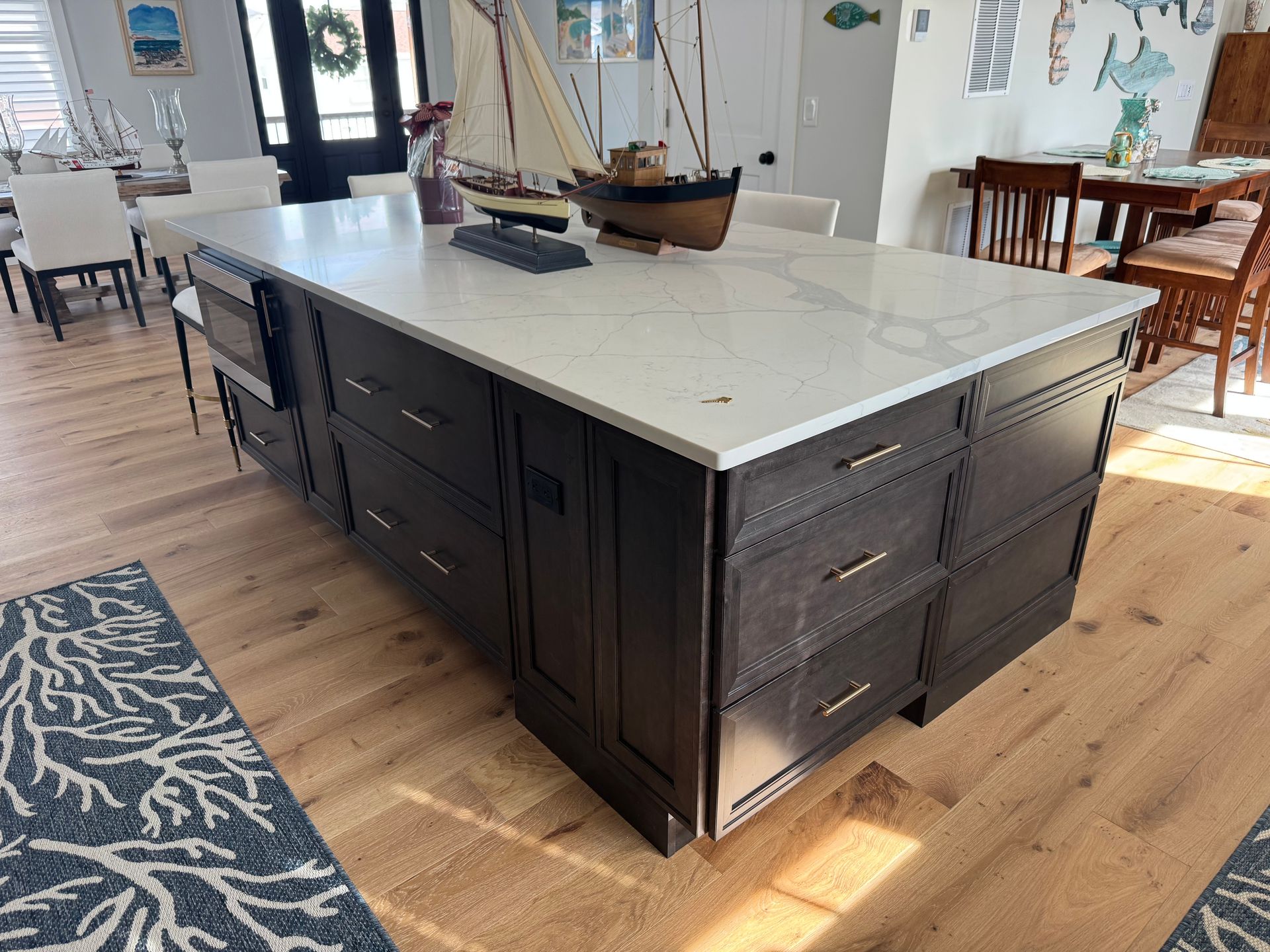 Kitchen island with a light countertop and dark cabinets in a bright, open room