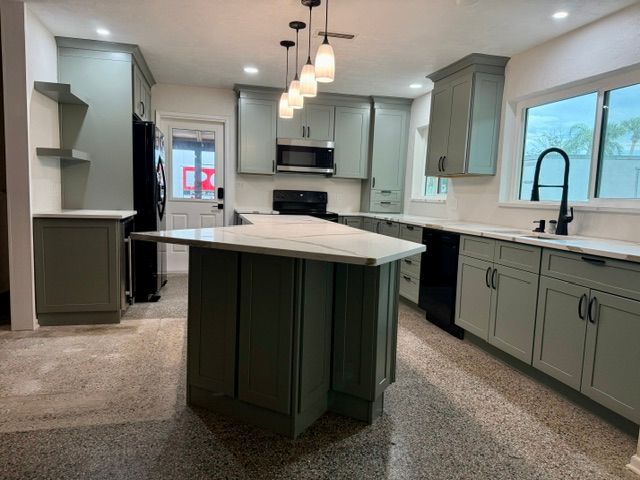Modern kitchen with gray cabinets, white countertops, central island, and pendant lights.