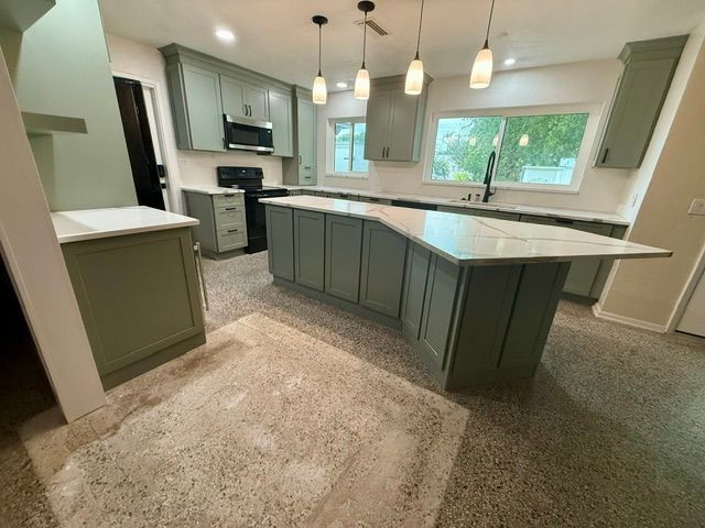 Modern kitchen with gray cabinets, white countertops, island, pendant lights, and large window