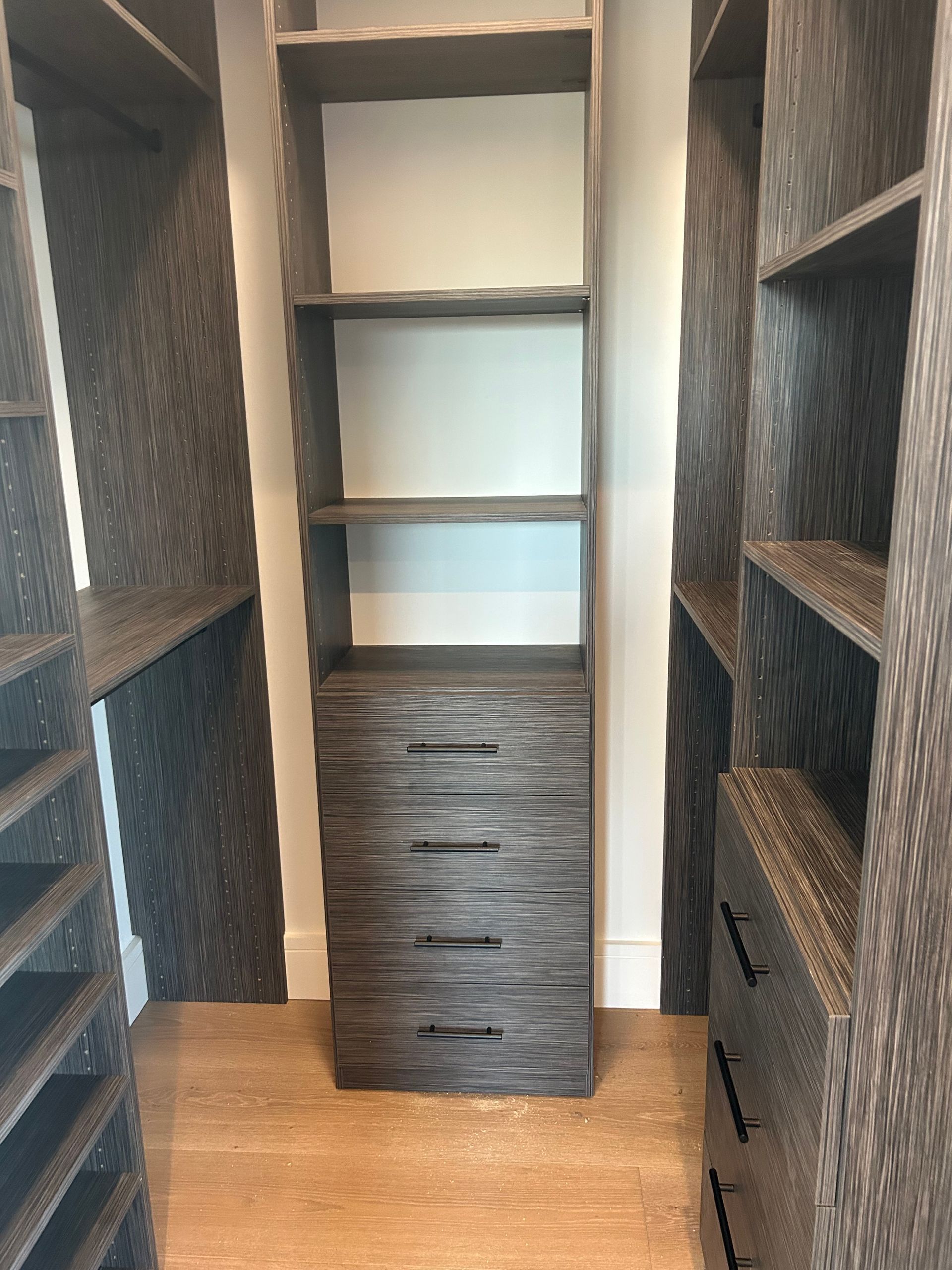 Walk-in closet with shelves and drawers. Woodgrain finish, neutral tones.