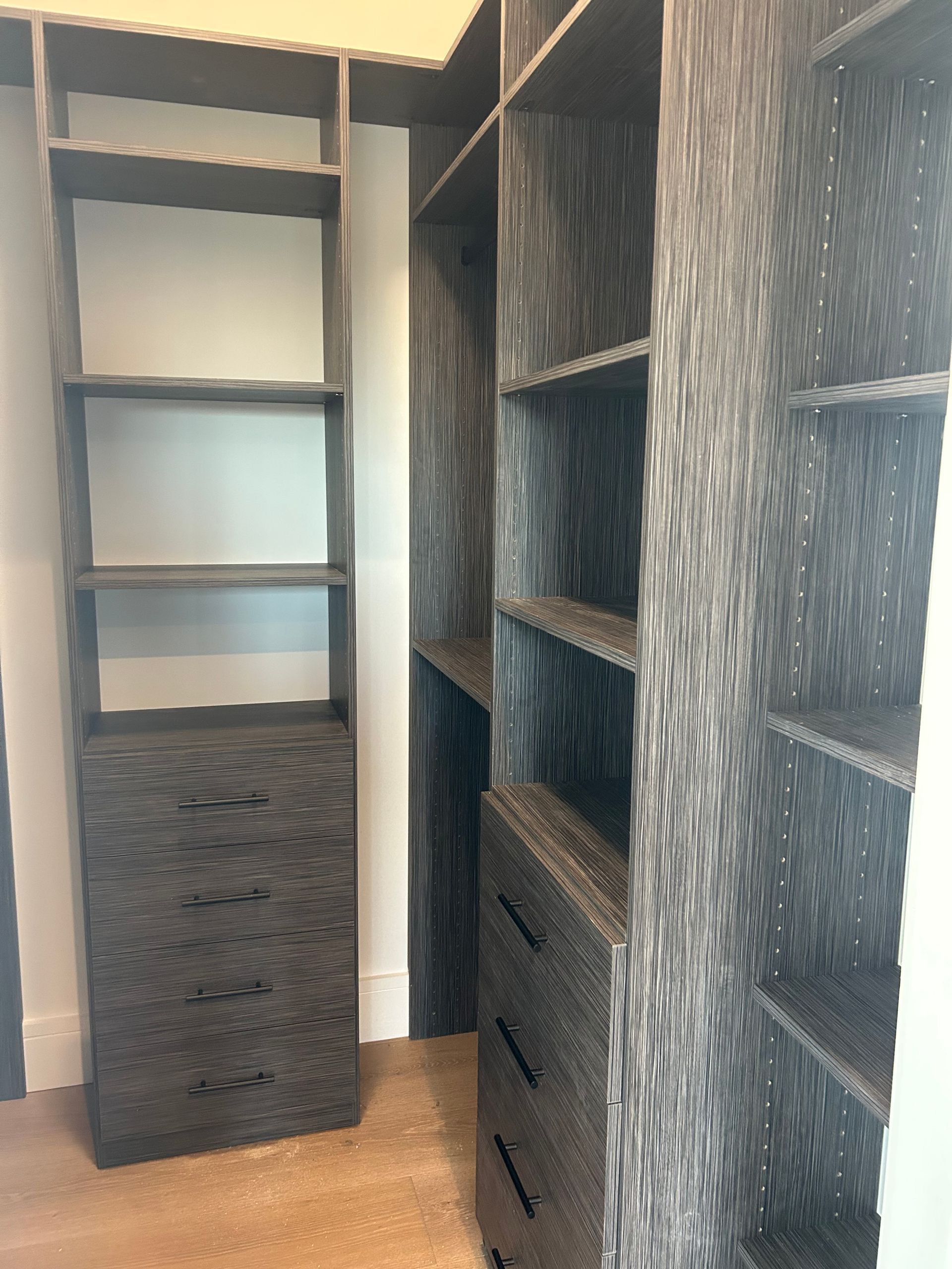 Dark wood closet shelving unit with drawers and open shelves.