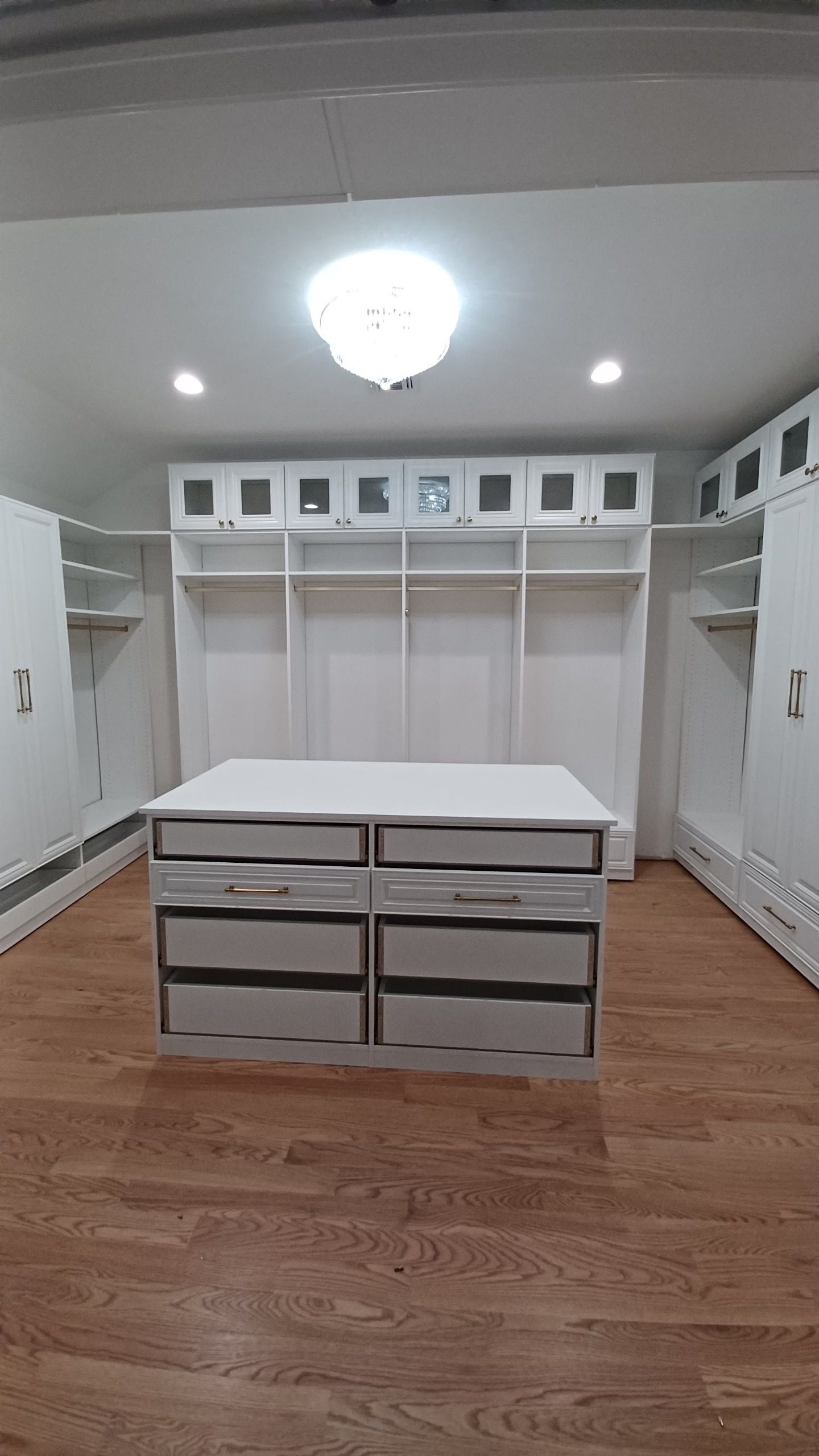 White closet with center island; light wood floor.