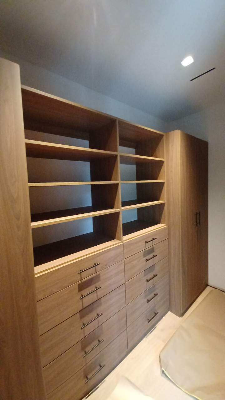 Wooden custom closet with drawers and shelves, built-in to a room.