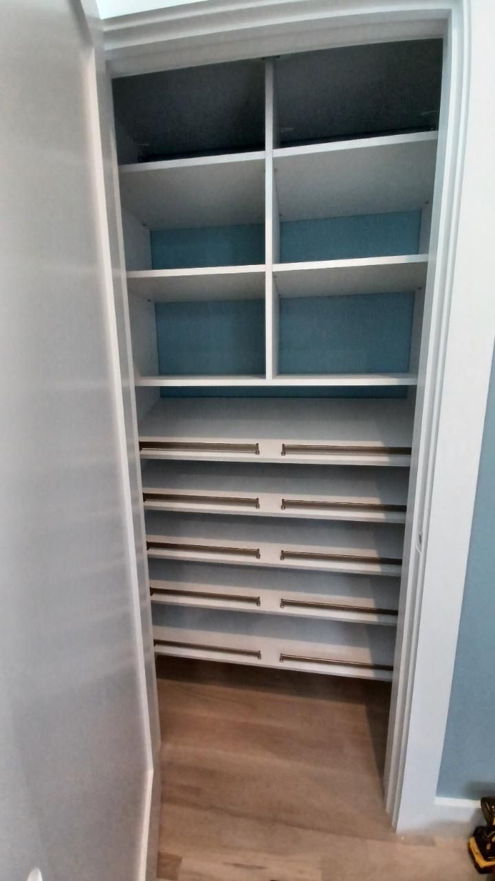 White closet shelves with blue backing and wooden floor.