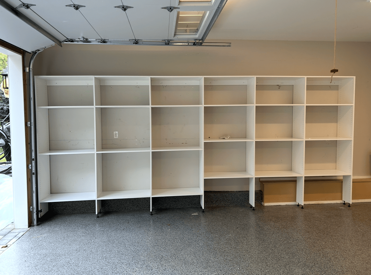 White shelving units against a beige wall in a garage.
