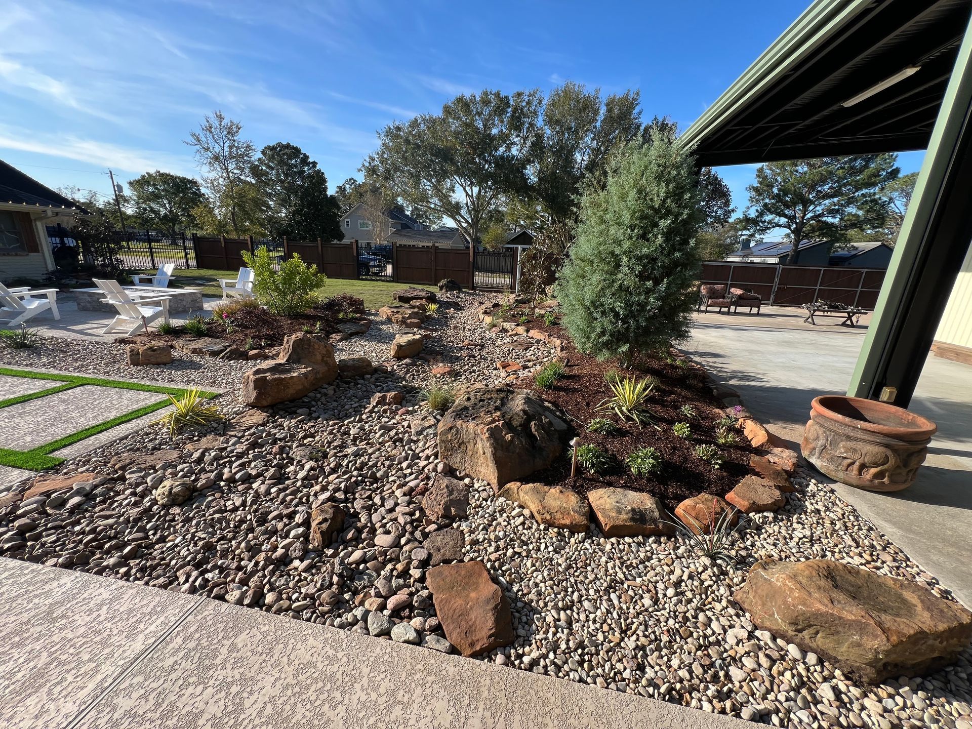 Rock garden with gravel, succulents, and a small tree under a bright blue sky.