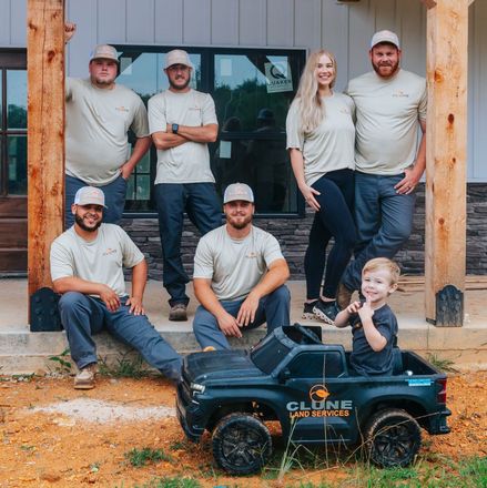 A group of people posing for a picture with a toy truck that says Clune