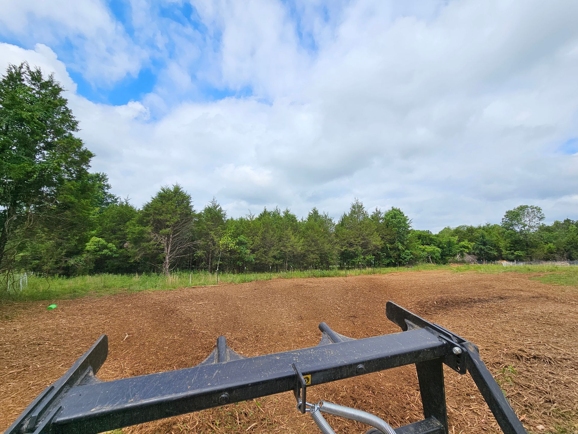 A tractor is sitting in a field with trees in the background.