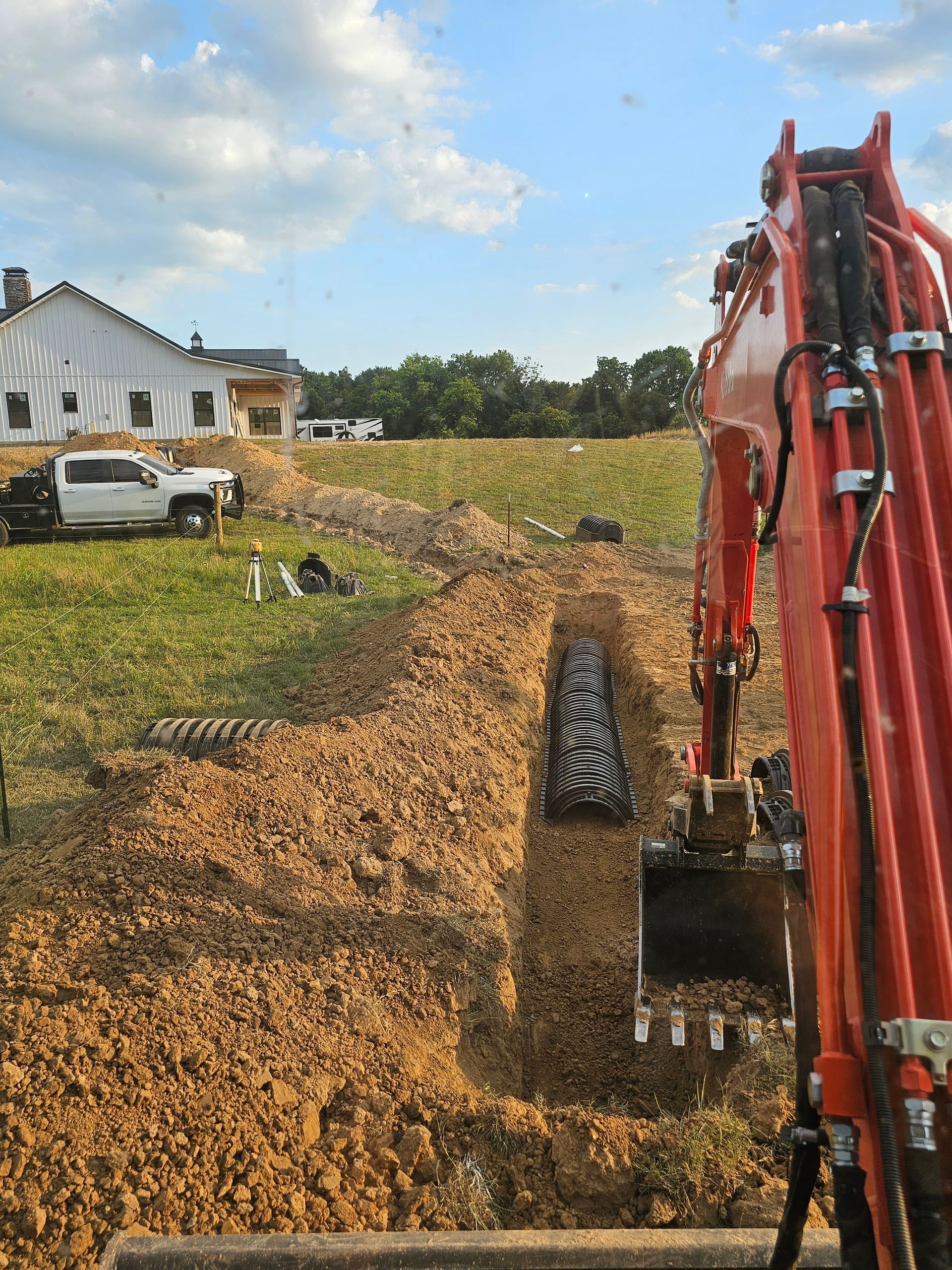 A red excavator is digging a hole in the dirt in front of a house.