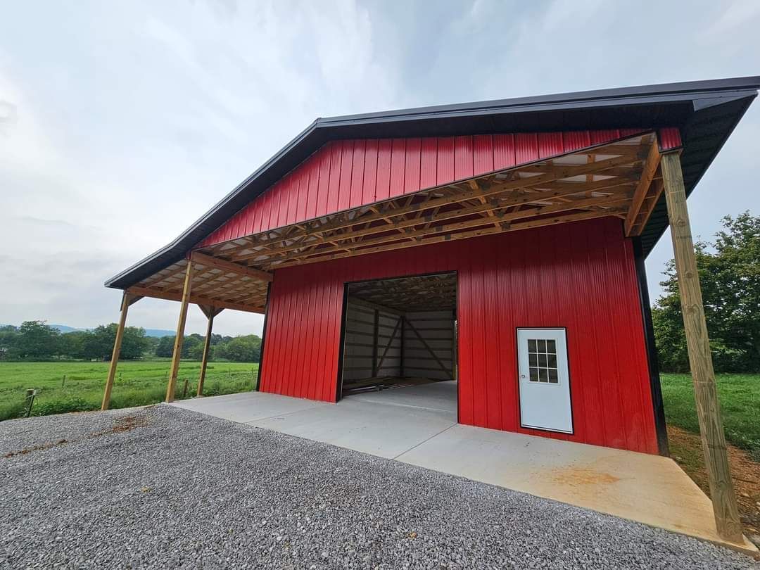 Red barn with concrete slab, gravel, and an open doorway under a wooden canopy