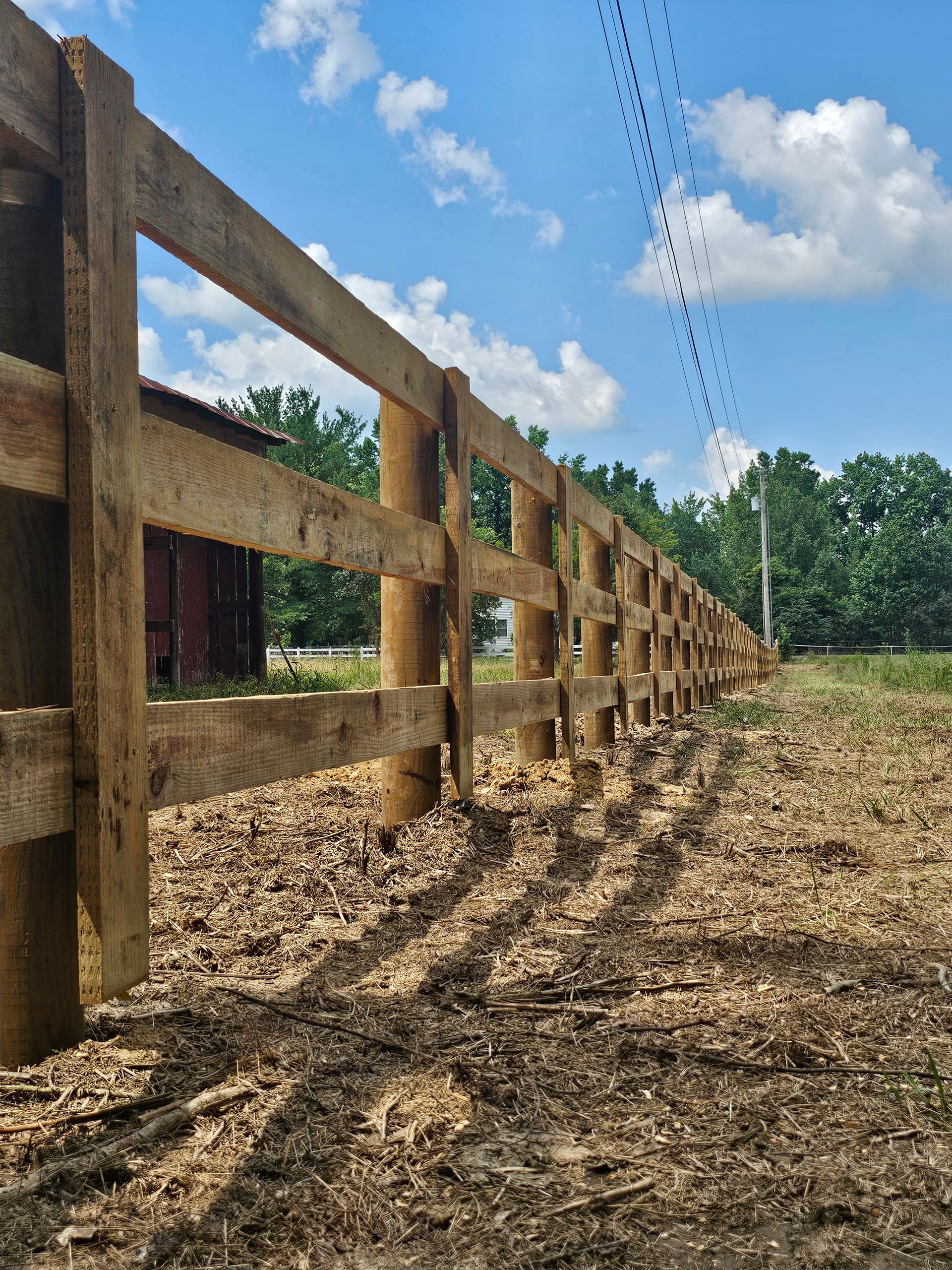 A wooden fence is sitting in the middle of a dirt field.