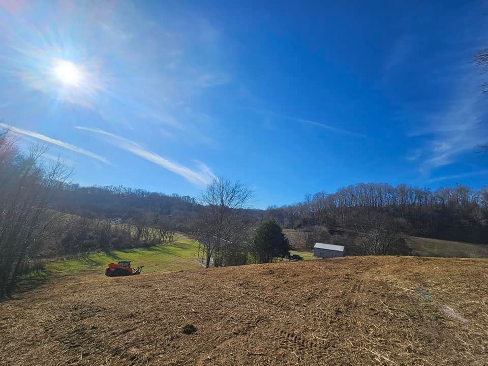 A tractor is plowing a field on a sunny day.
