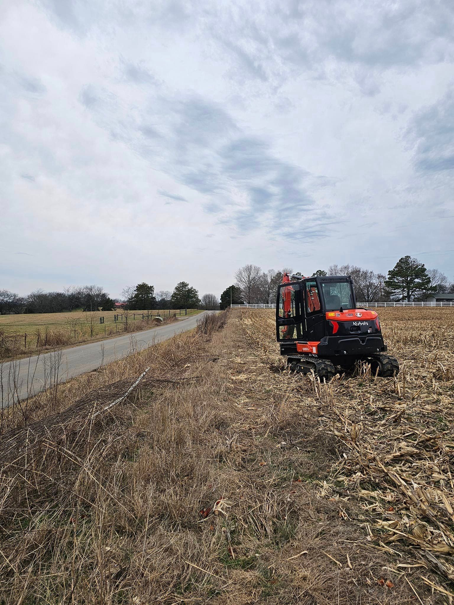 A tractor is driving down a dirt road in a field.