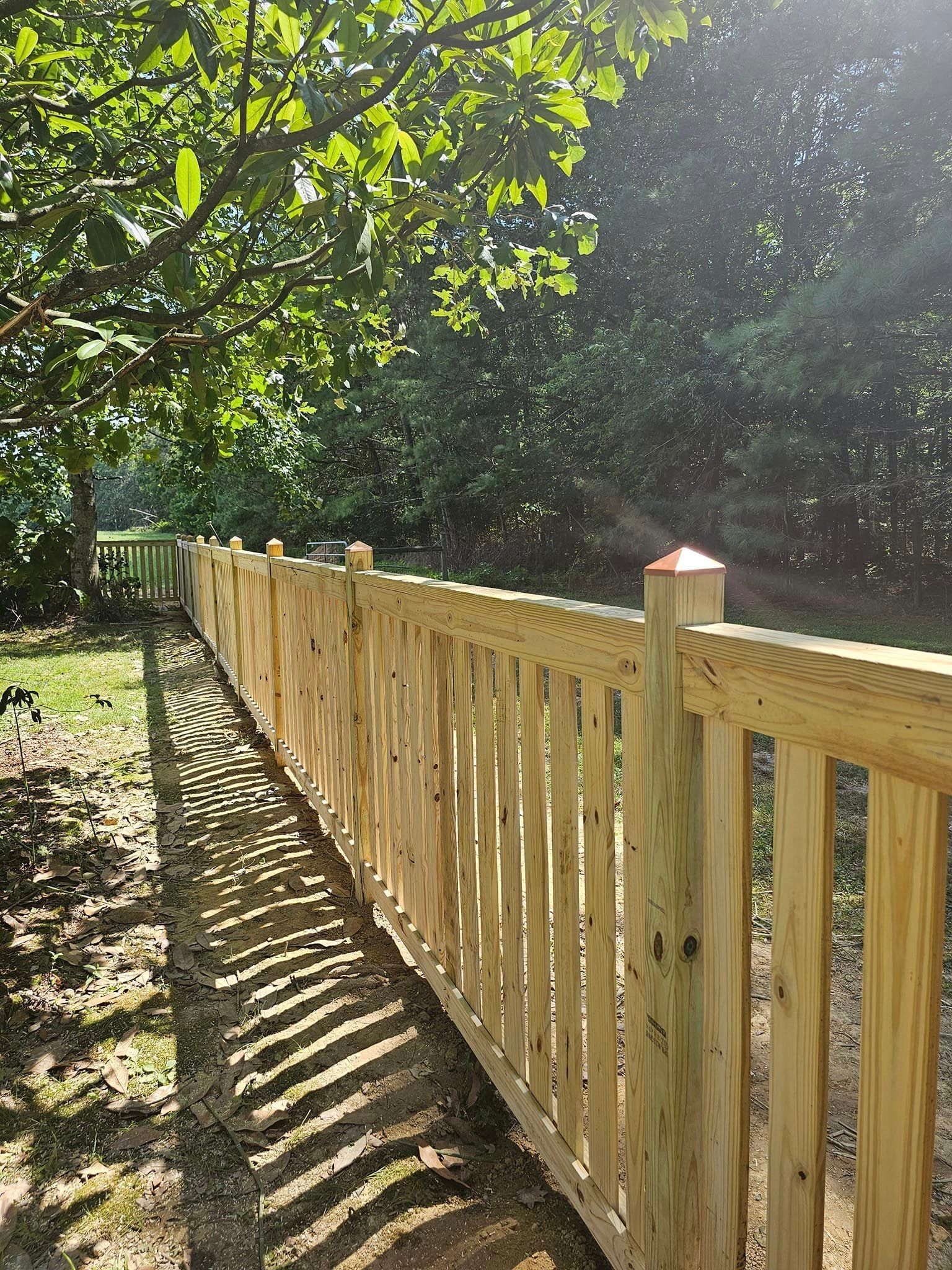 A wooden fence is surrounded by trees in a yard.