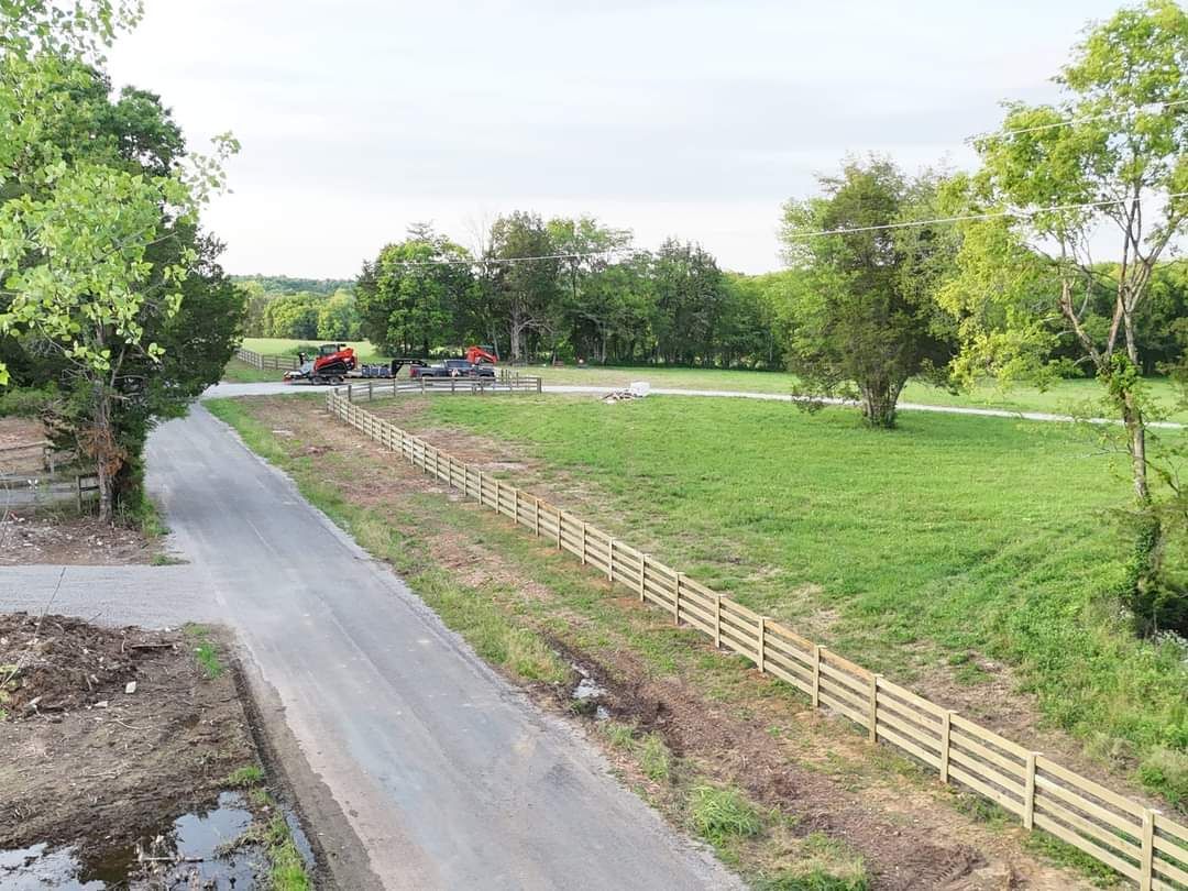 An aerial view of a road leading to a field with a wooden fence.