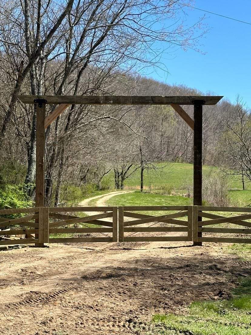 A wooden fence with a gate in the middle of a field.