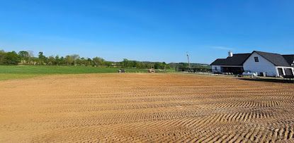 A large, cleared field, with a house on the right, under a blue sky