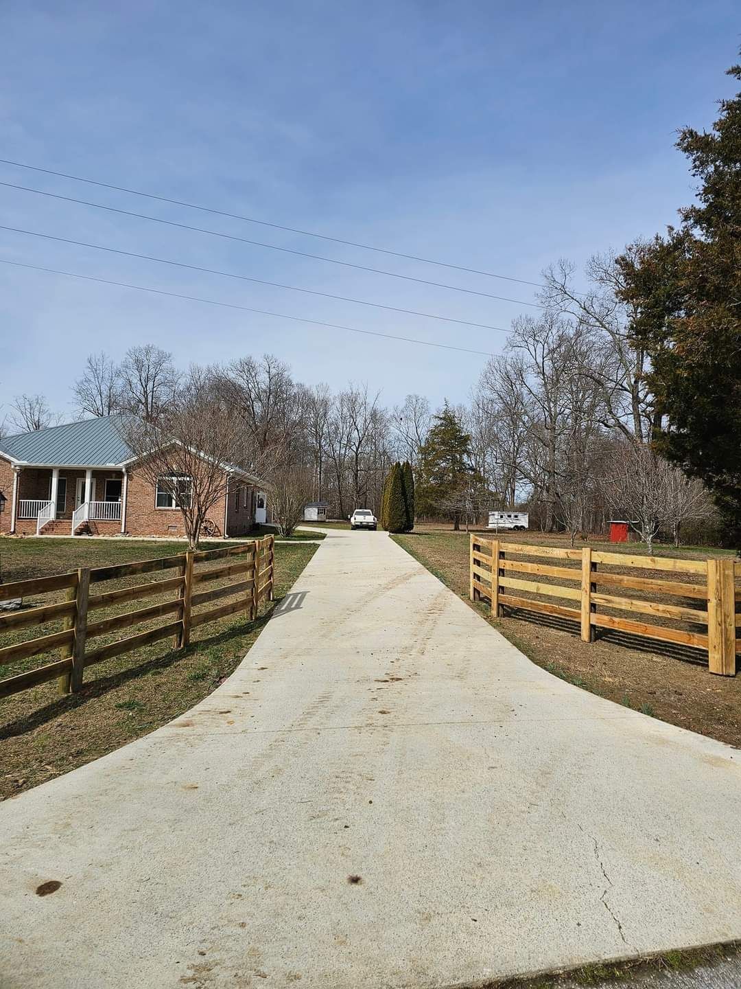 A driveway with a wooden fence leading to a house.