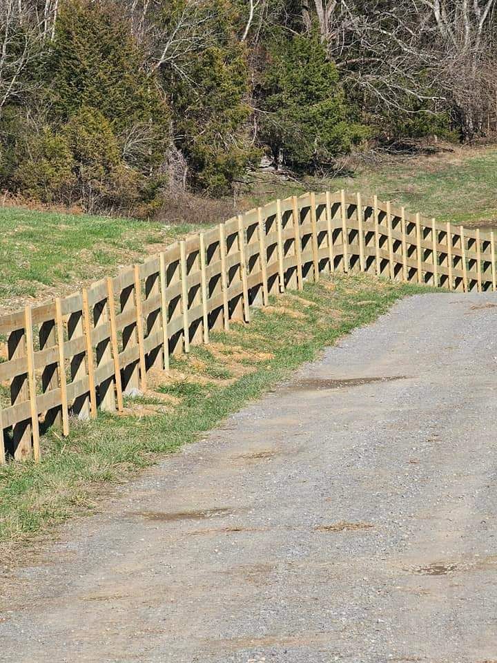 A wooden fence along the side of a gravel road.