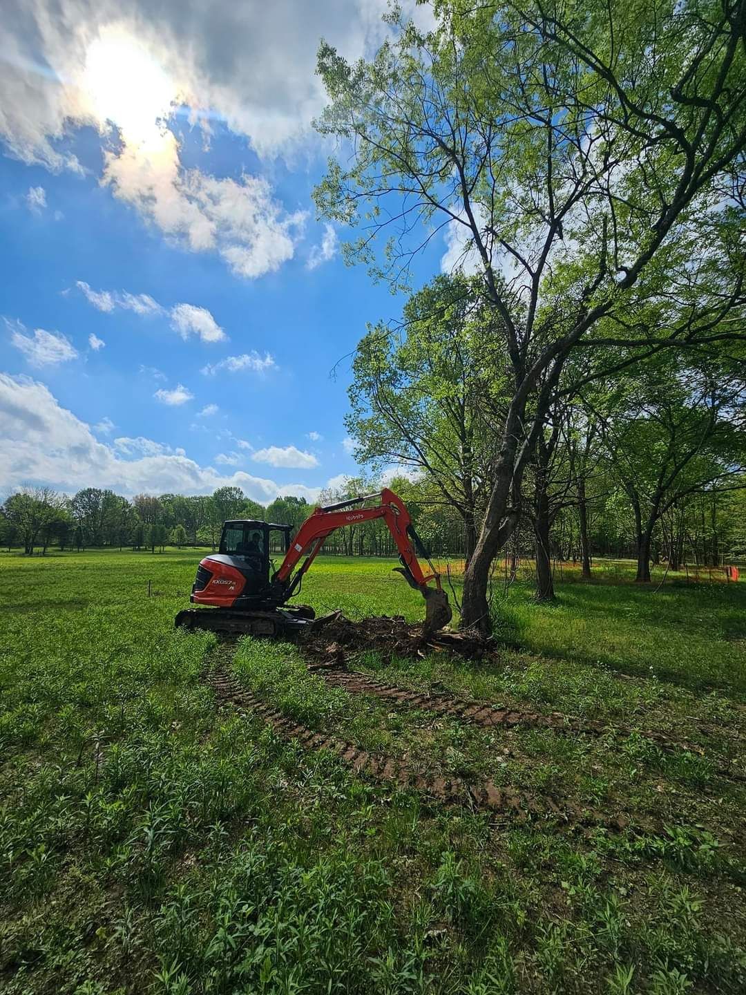 An excavator is digging a hole in a grassy field.