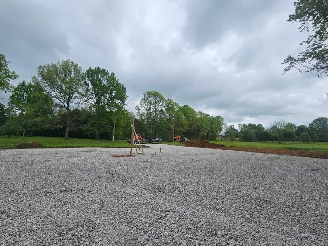 There is a lot of gravel in the middle of a field with trees in the background.